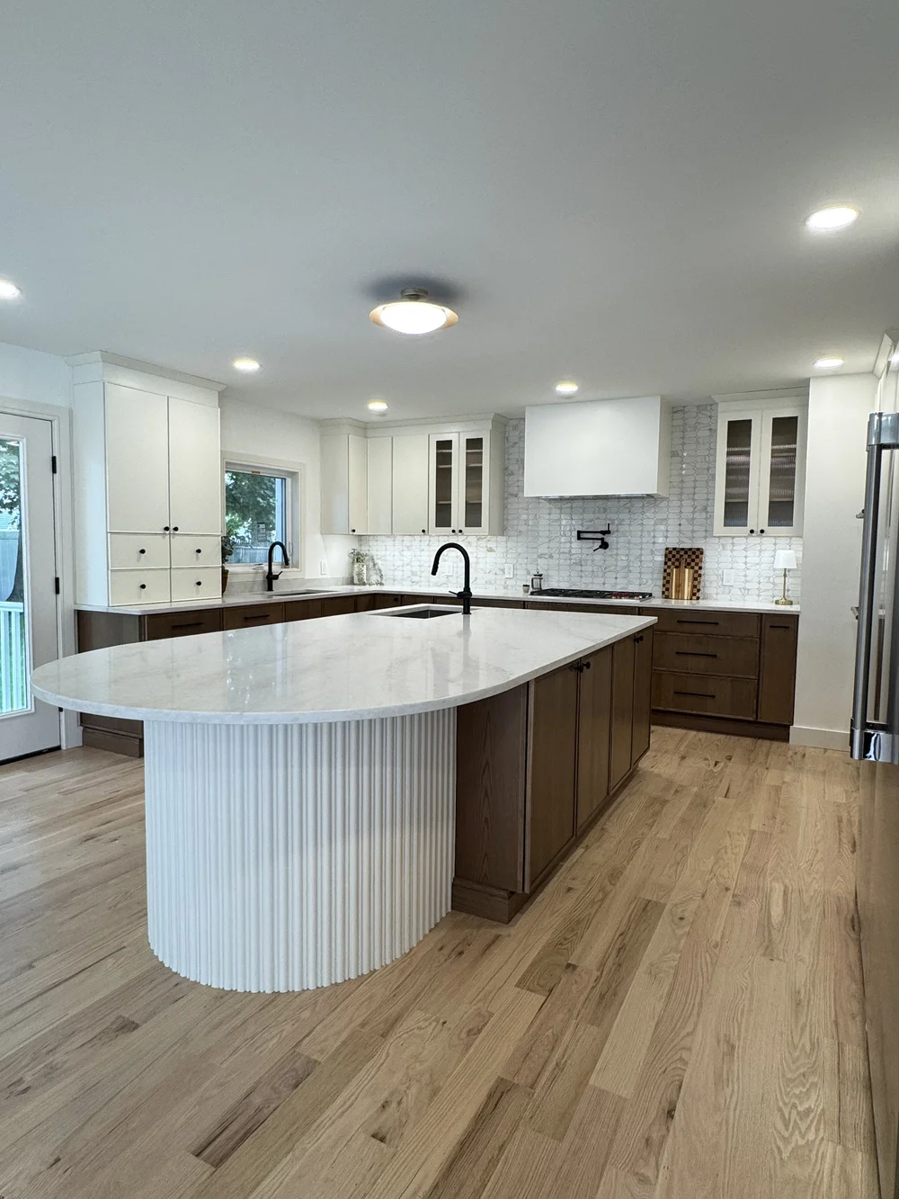 Renovated John Place kitchen in Bergenfield with a fluted white curved island, quartz countertops and white oak floors