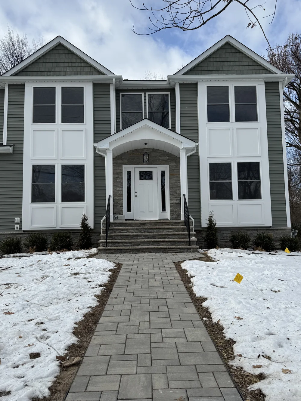 Boulevard project exterior: two-story home with grey siding, white trim, columned front entry and paver walkway