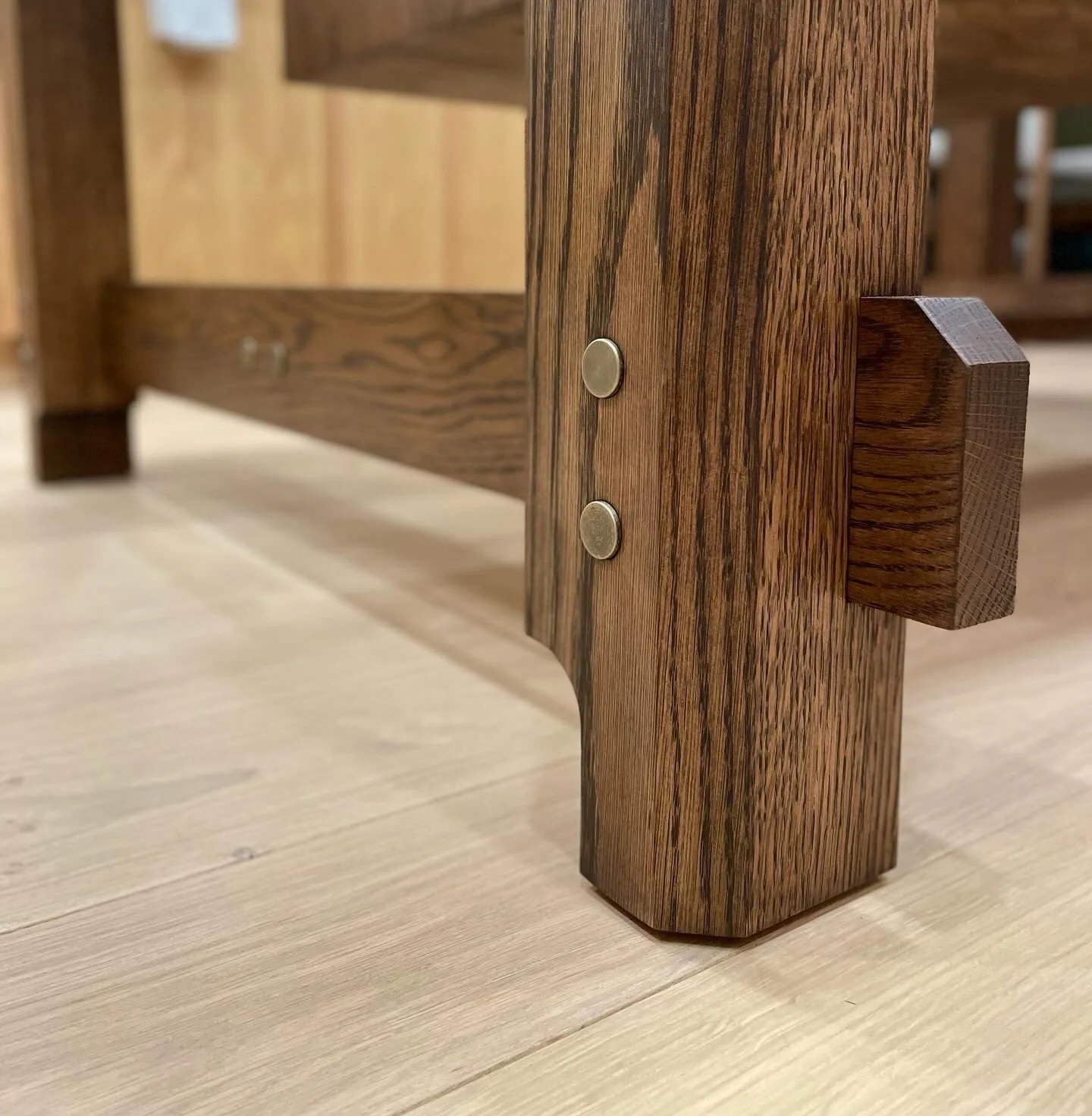 Close-up of a wooden furniture piece showing a joint with bronze pins, highlighting the dark wood grain and craftsmanship.