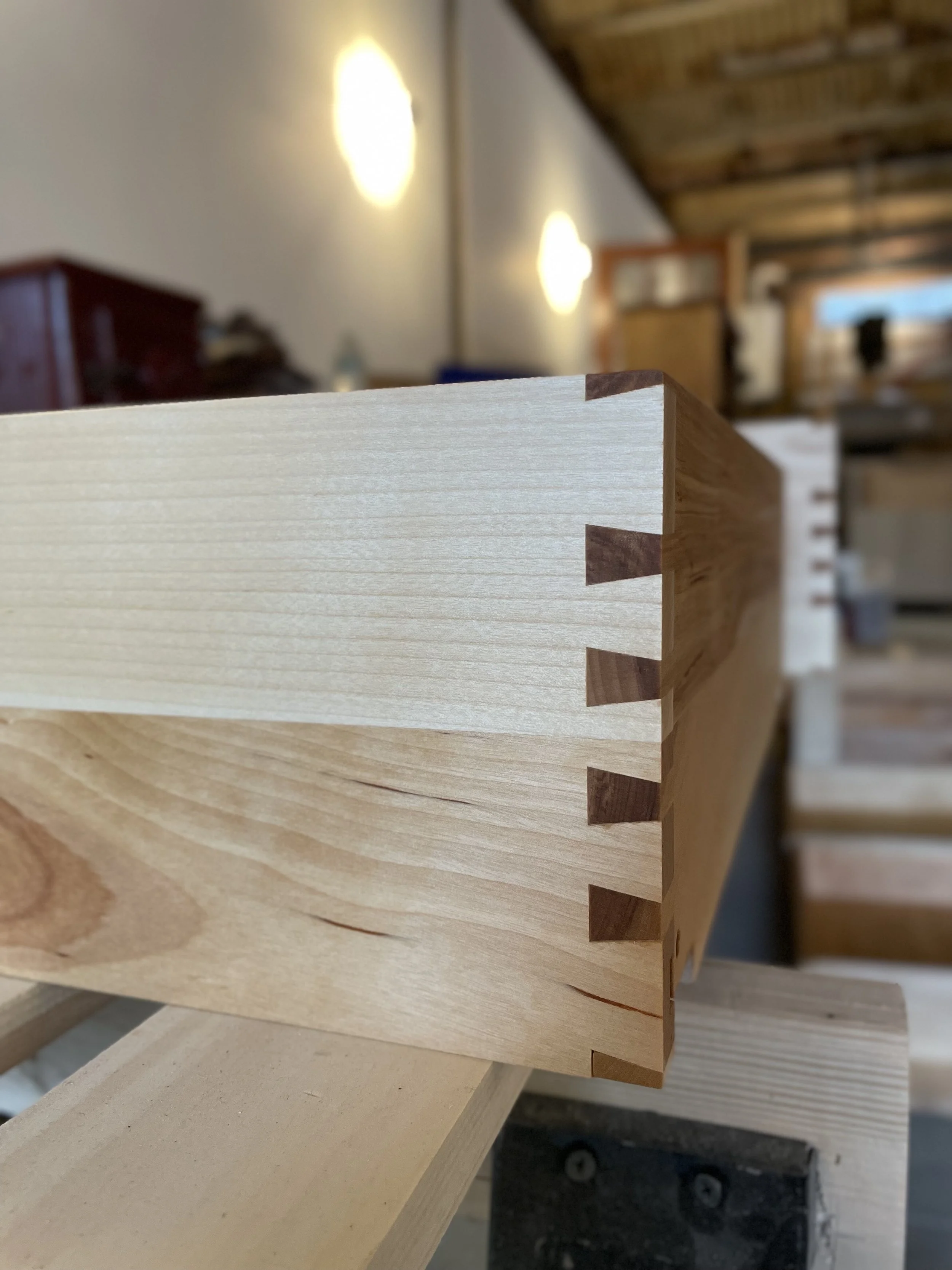 Close-up of a wooden box corner with dovetail joints in a woodworking shop.