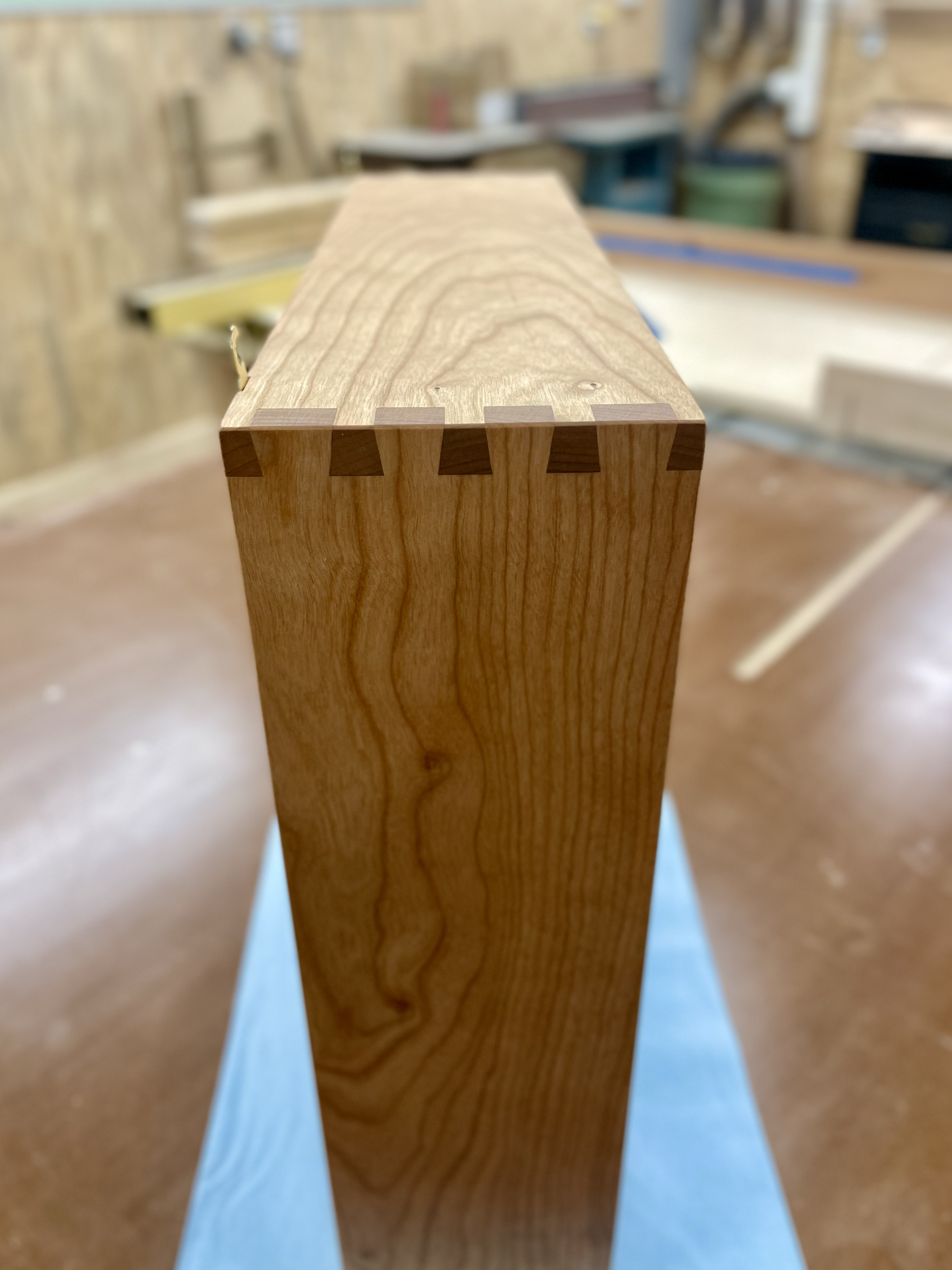 Close-up of a wooden piece with dovetail joints in a woodworking shop.
