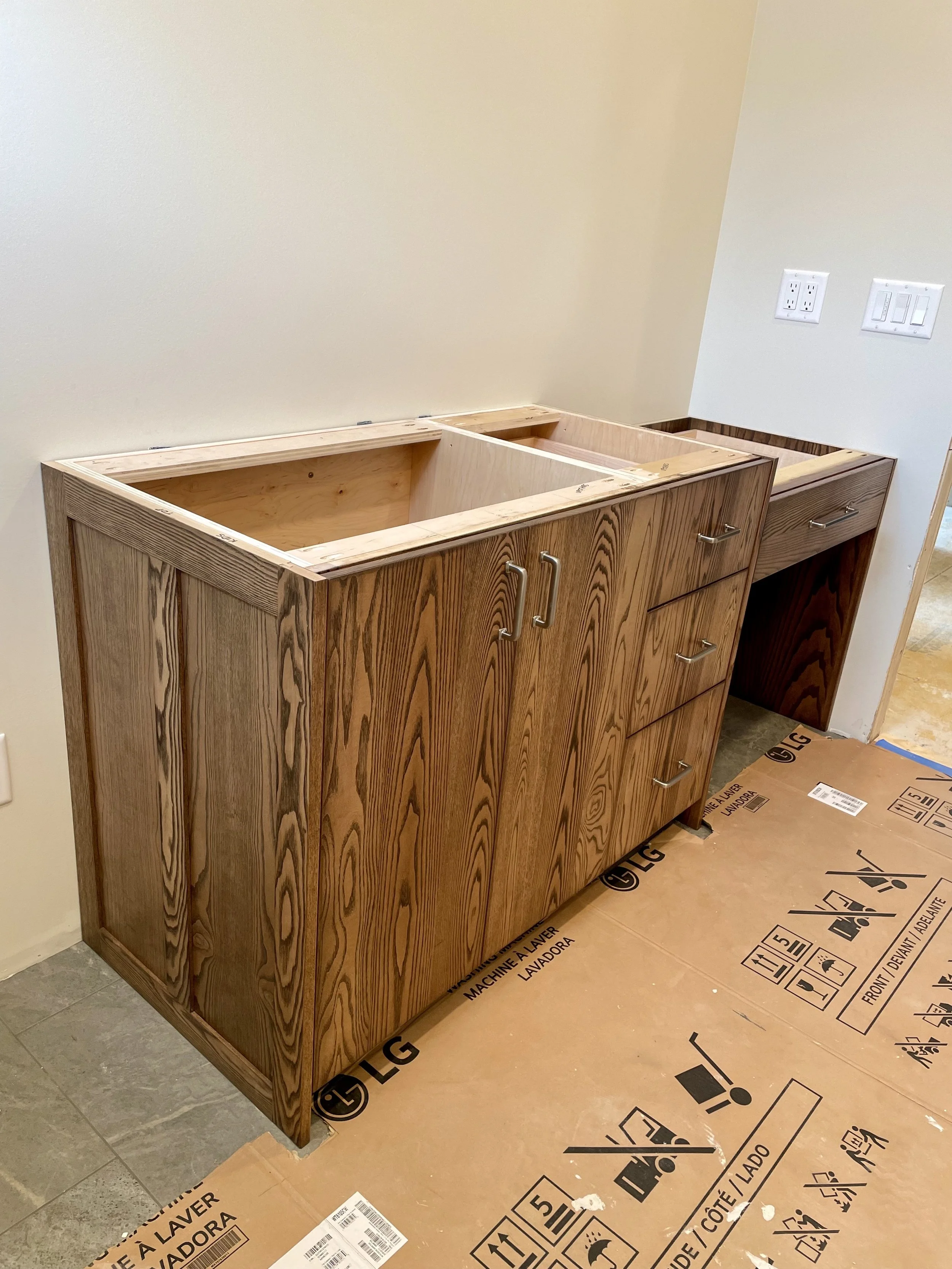 Wooden cabinets under construction in a room, with electrical outlets on the wall.