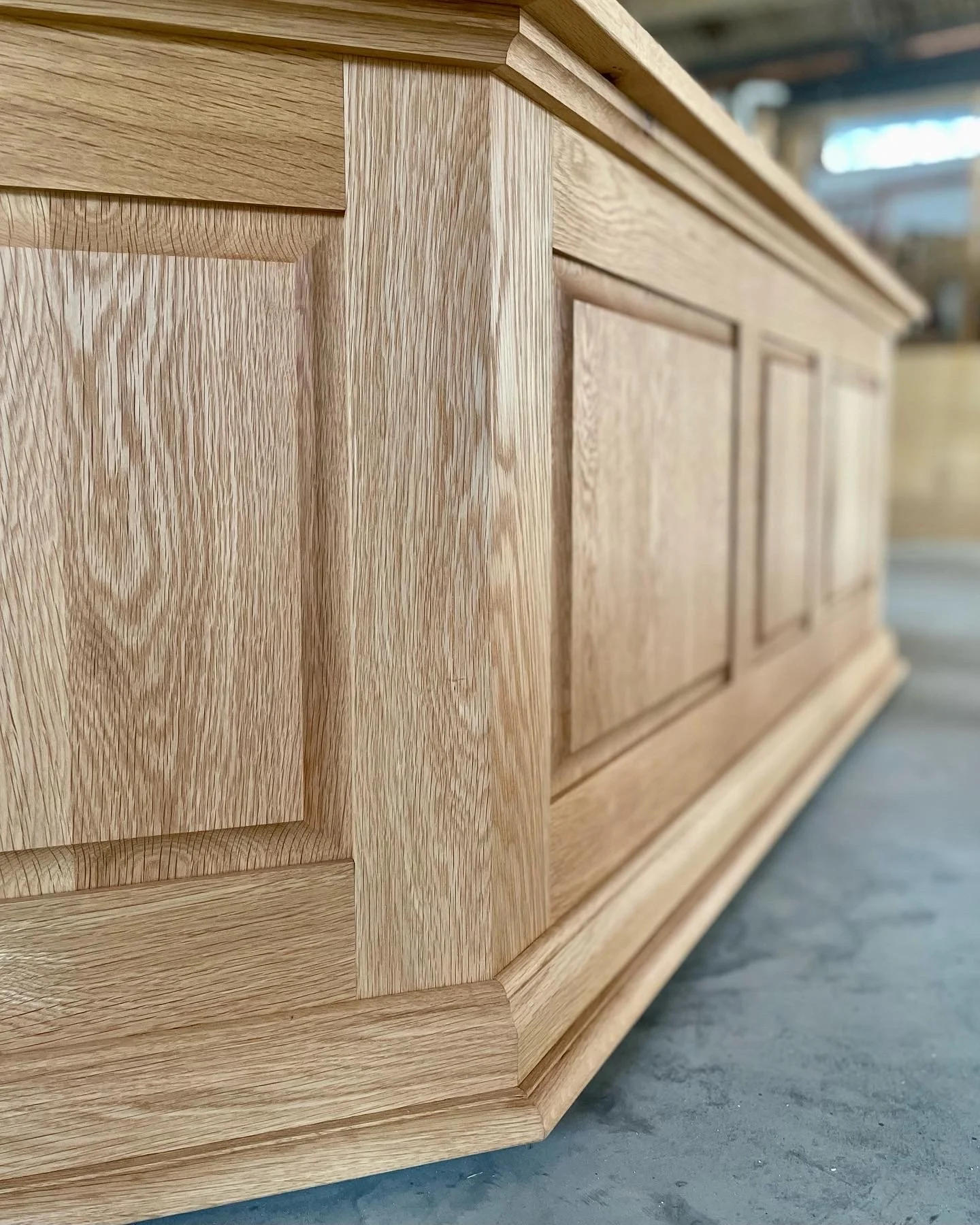 Close-up of a white oak cabinet with detailed craftsmanship and paneling, in a workshop setting.