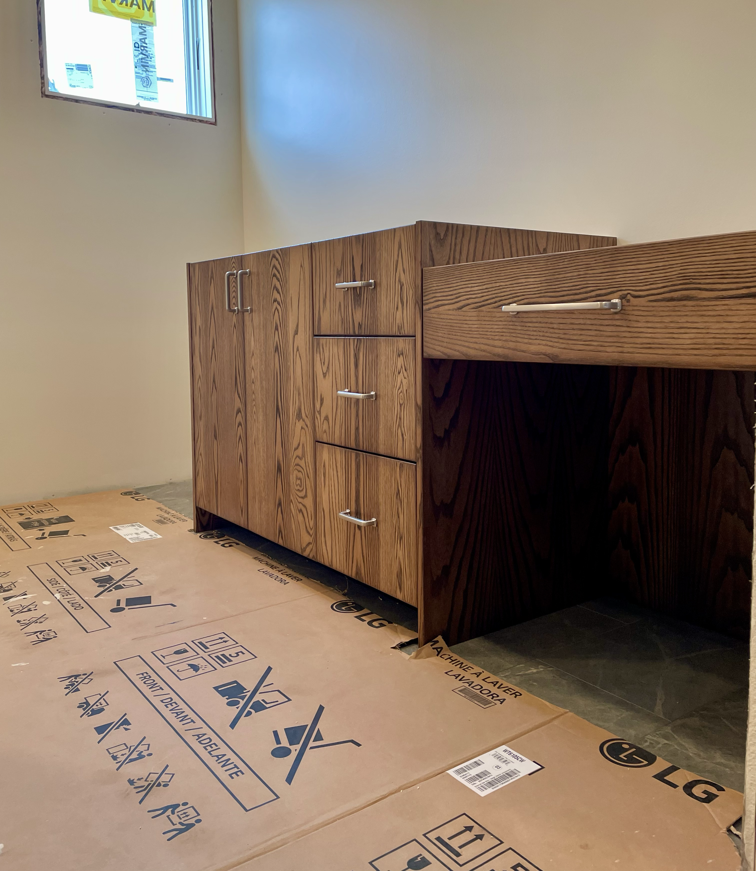 Wooden kitchen cabinet with metal handles in a room under construction or renovation.