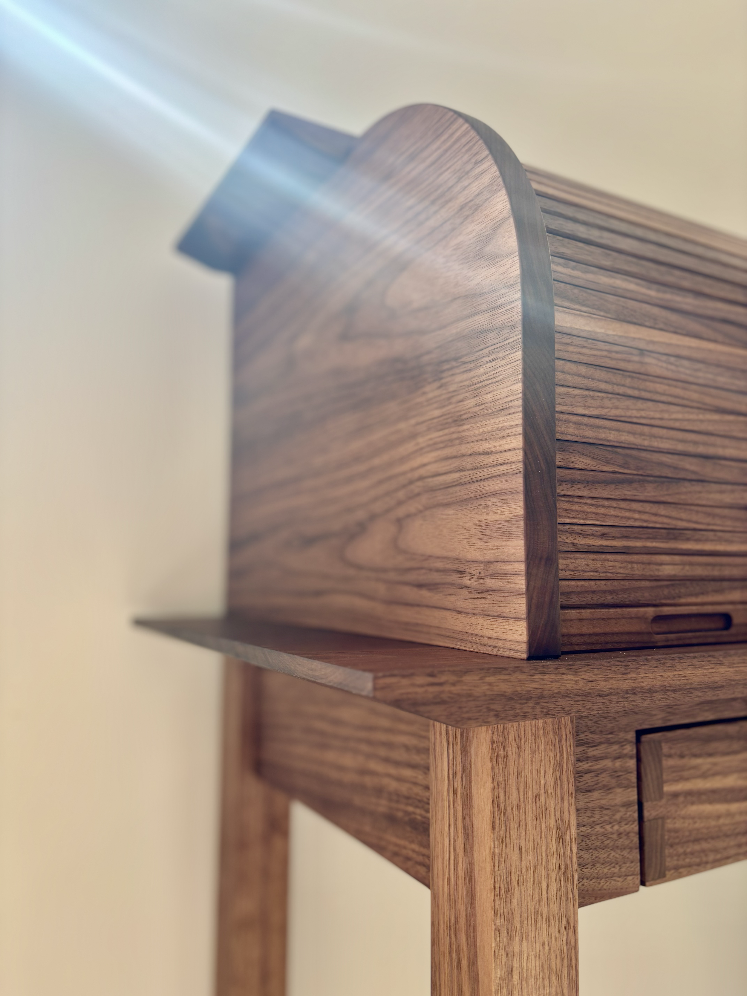 Close-up of a wooden side table with curved edges and textured grain, set against a plain background.