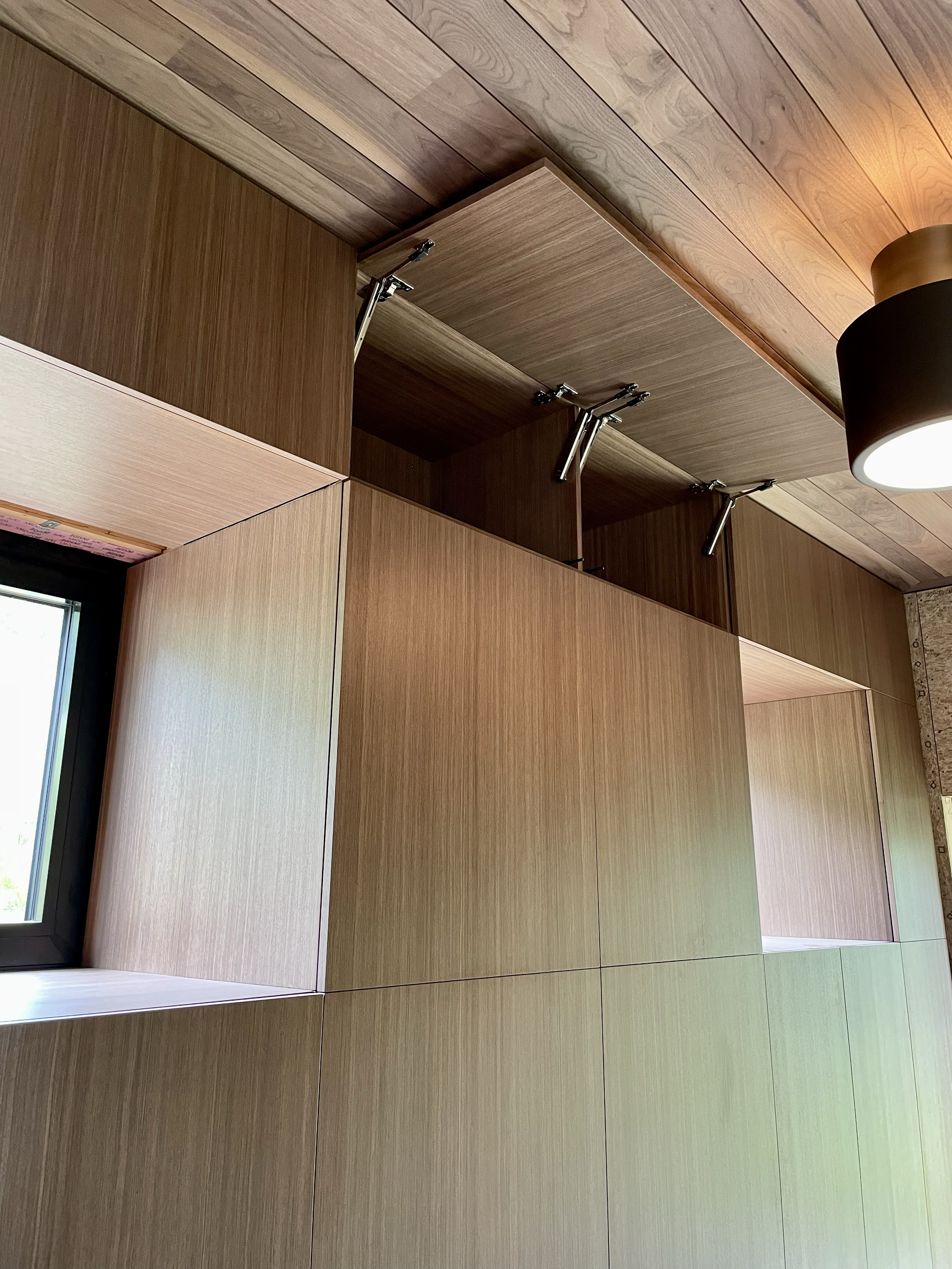 Wooden cabinets with one cabinet door open and hydraulic lift supports