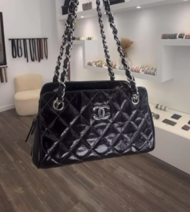 Sac à main Chanel noir en cuir matelassé avec chaîne en métal et logo Chanel, suspendu dans une boutique de mode.