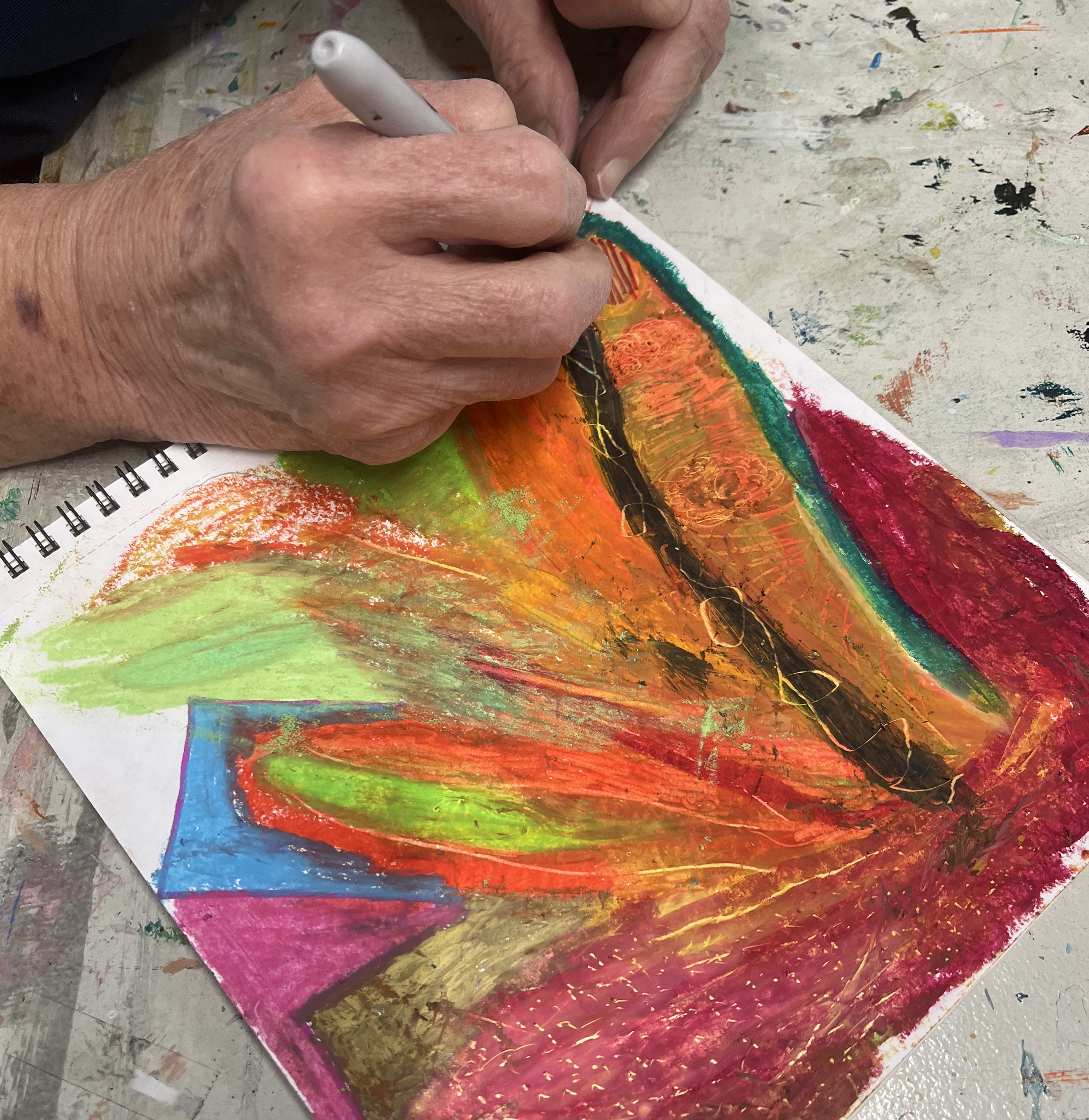 Close up of an older woman's hand working on a colorful abstract drawing