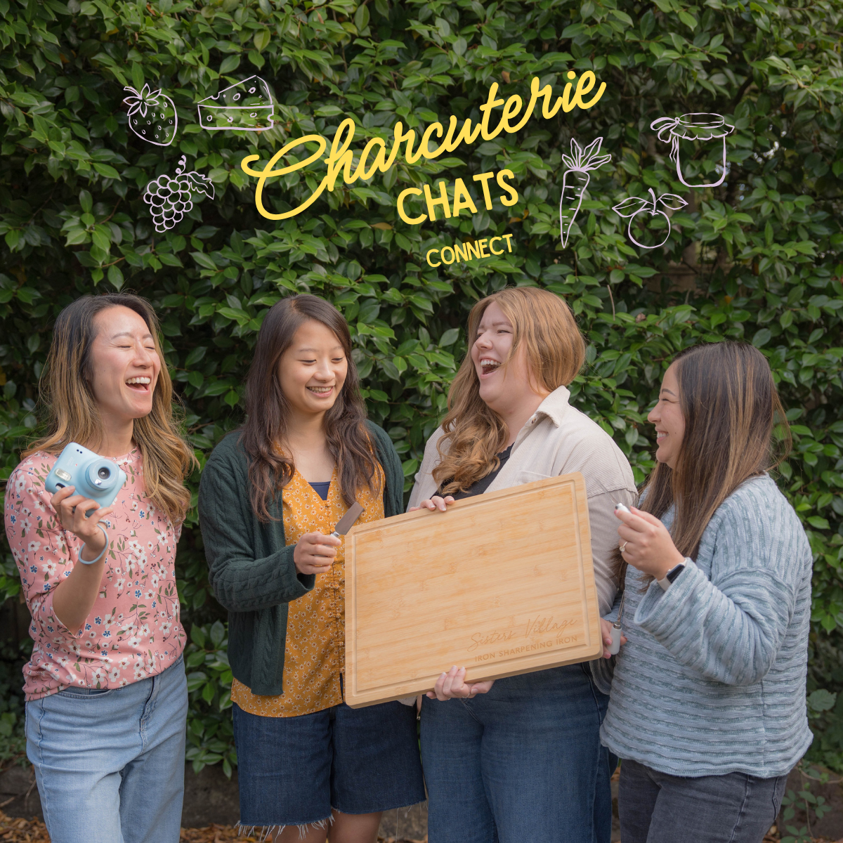 Four women laughing and sharing a moment outdoors, holding a wooden cutting board, with a green leafy background. Illustrations of strawberries, cheese, grapes, carrots, a jar, and an apple are above them with the text 'Charcuterie Chats Connect' in yellow.