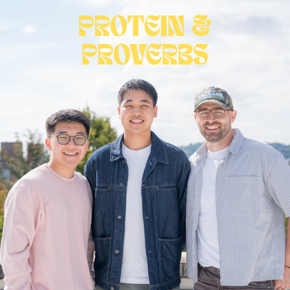 Three men standing outdoors with a cloudy sky and trees in the background, smiling for the camera. The text 'Protein & Proverbs' is displayed above them.