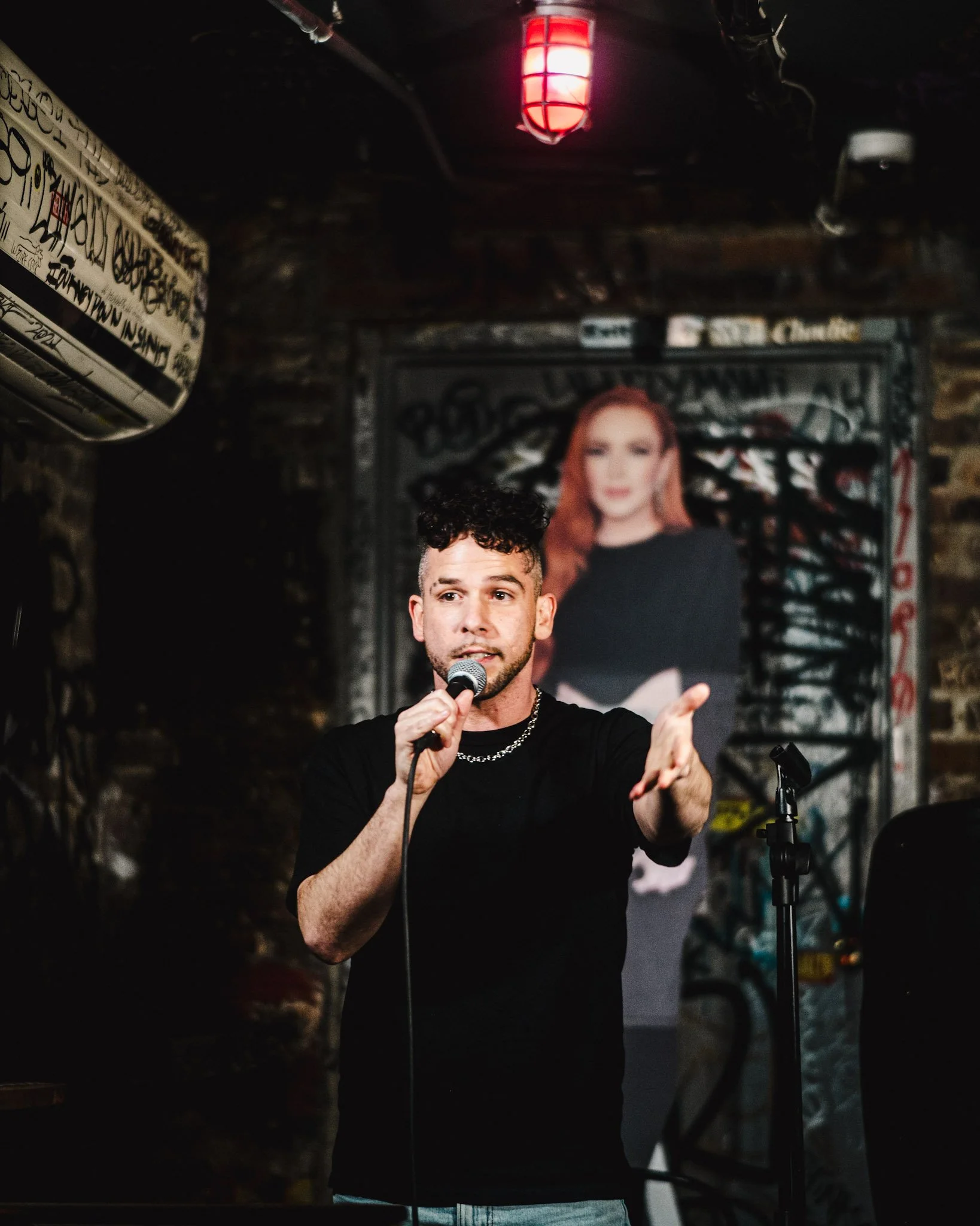 Steven Zakari holding a microphone and performing in a Brooklyn bar.