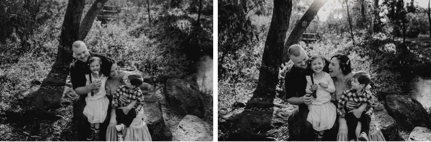 19_DTEV-83_DTEV-81_Black and white Family portrait sitting on a rock with the sun shining behind them, piercing through the trees. .jpg