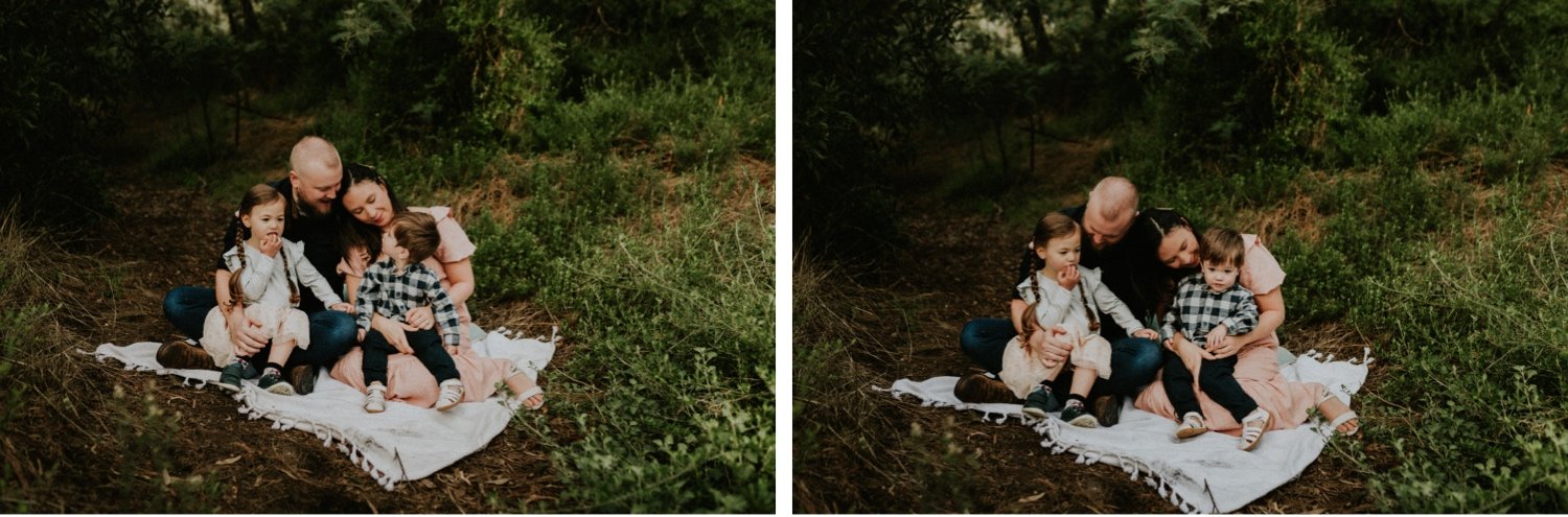 08_DTEV-21_DTEV-22_Family sits snuggled up on white picnic rug and look at each other. .jpg