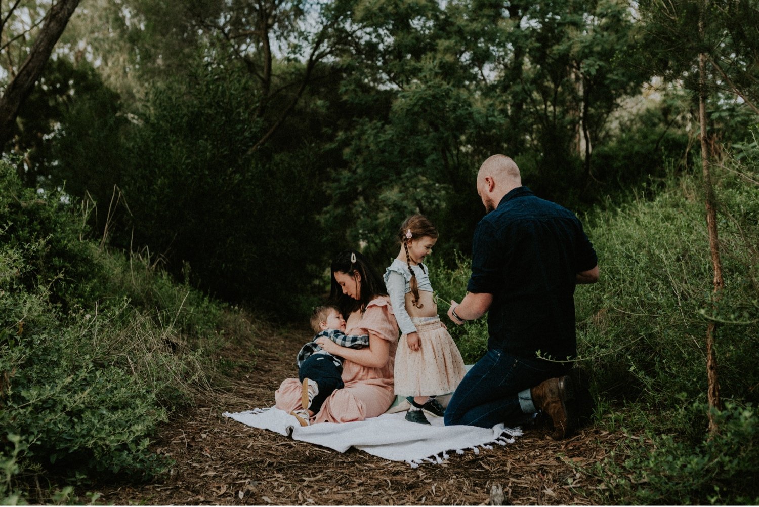 01_DTEV-1_Colour photos of the family seating in a bush setting. The mother is holding their son while the dad is feeding their 4 year old daughter using a feeding tube. .jpg