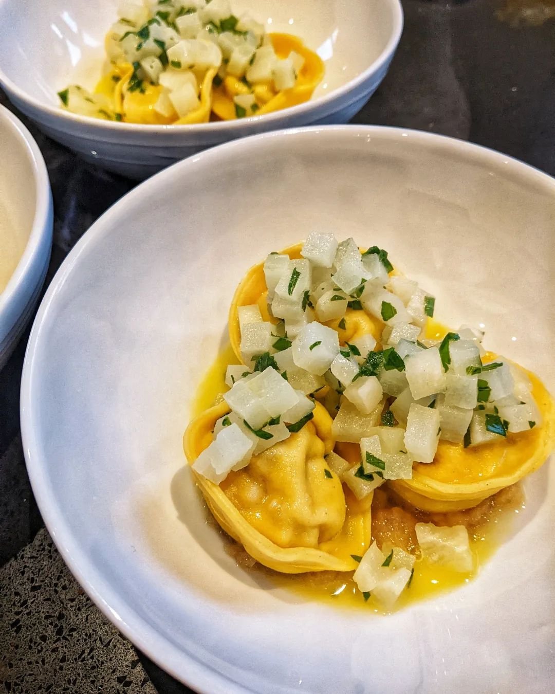 Smoked pork tortellini sitting on a bed of onion jam, with turnips and a chicken butter sauce ✨ last night's private dining event's starter was such a hit! Always love the process of making fresh pasta 🧡