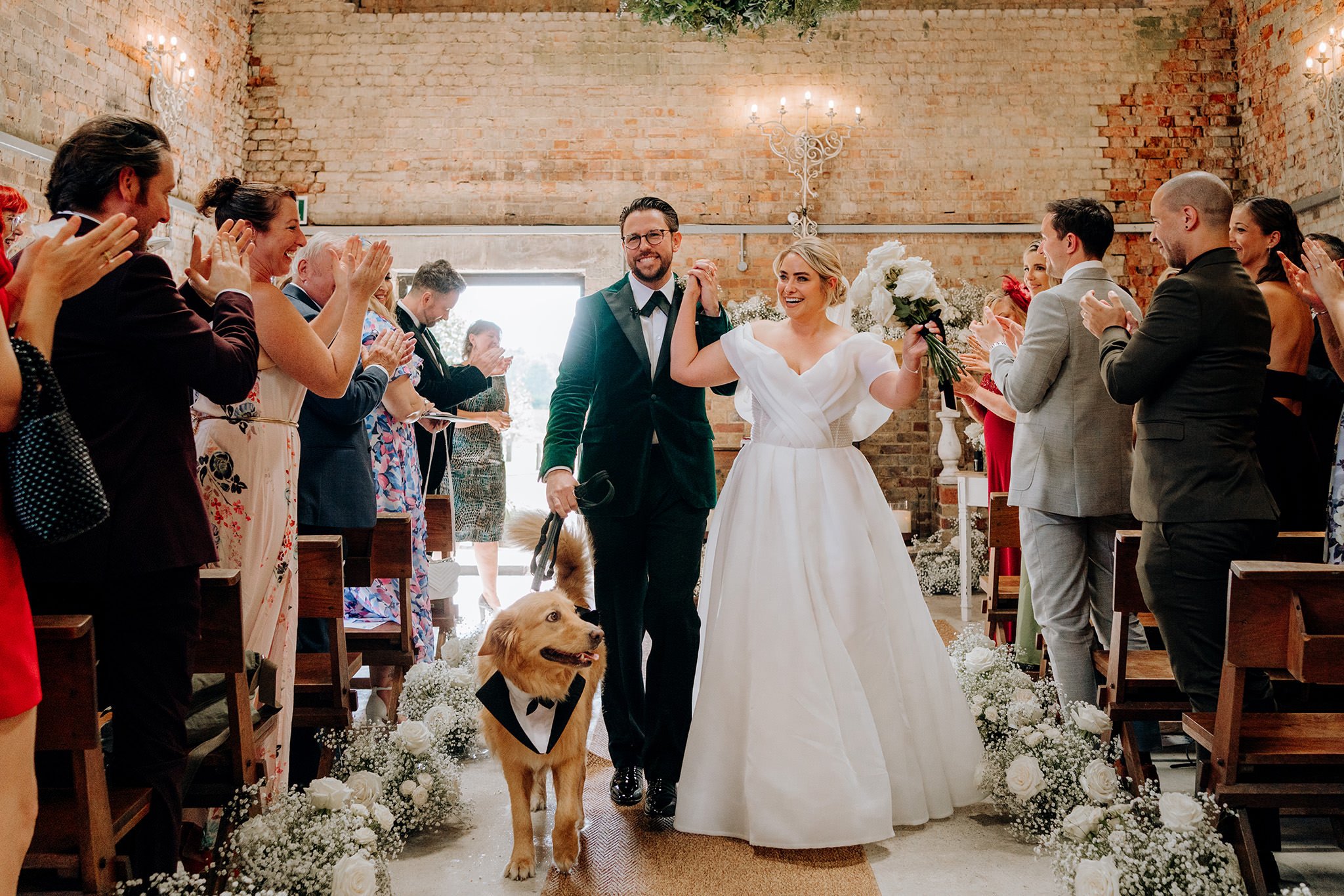 Bride and groom walking up the aisle with their dog