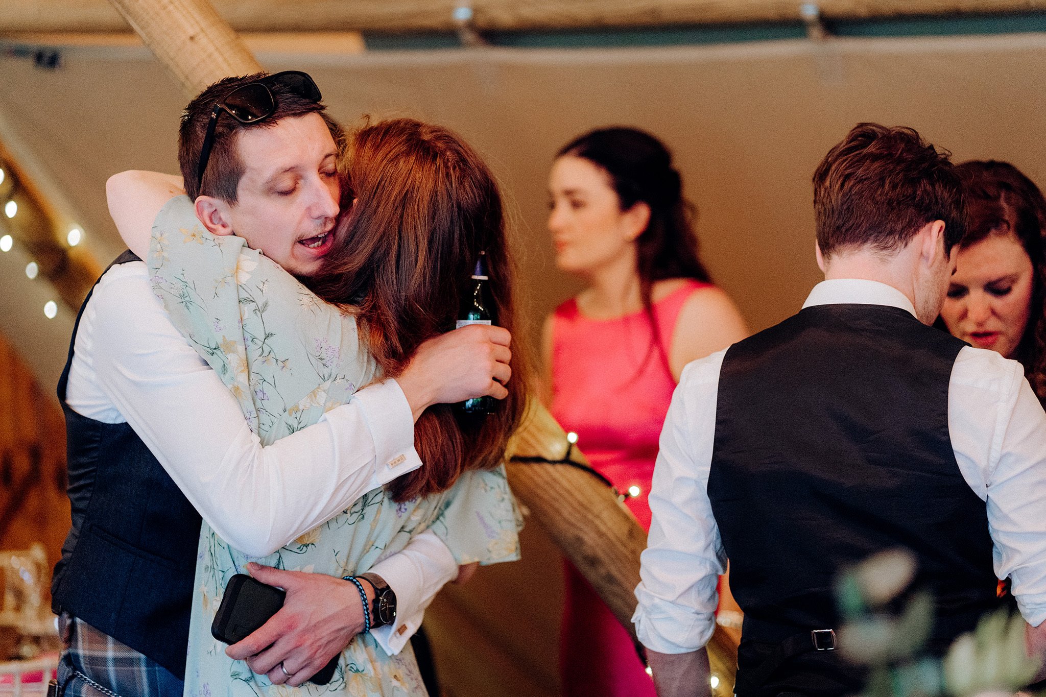 wedding guests share a hug at tipis at riley green