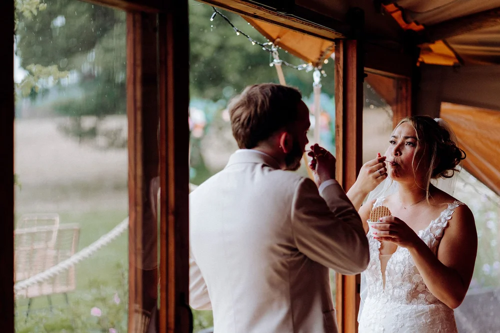 bride and groom eating ice cream, sheltering from the rain