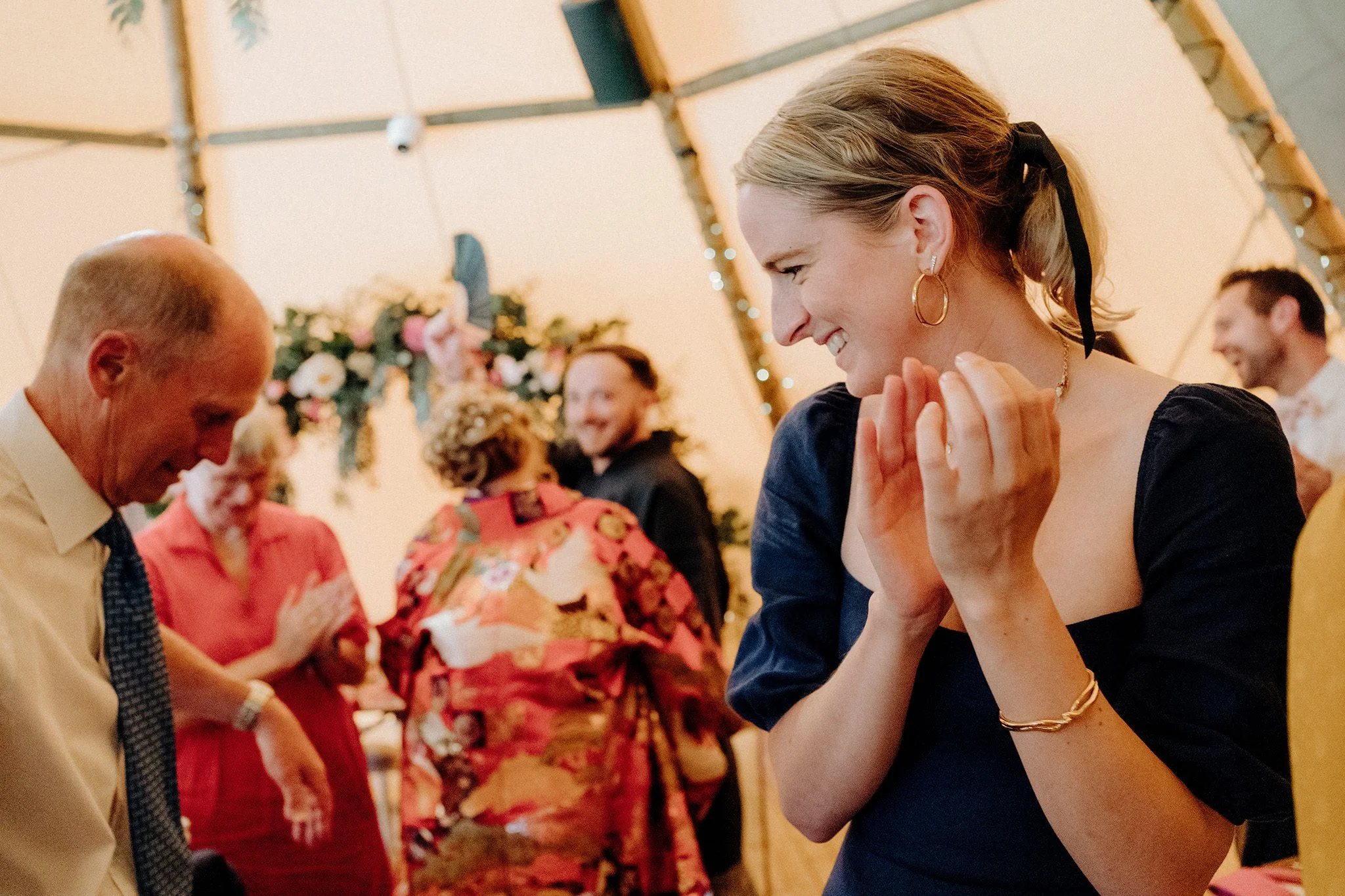 bride and groom arrive as guests applaud, tipis at riley green