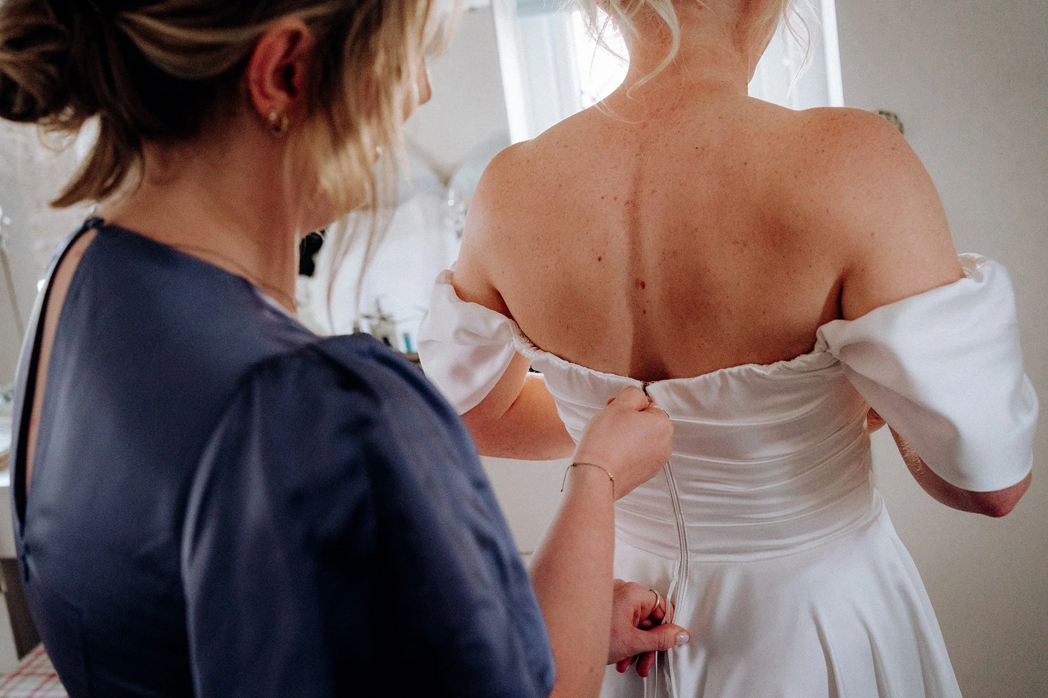 helping the bride into her dress