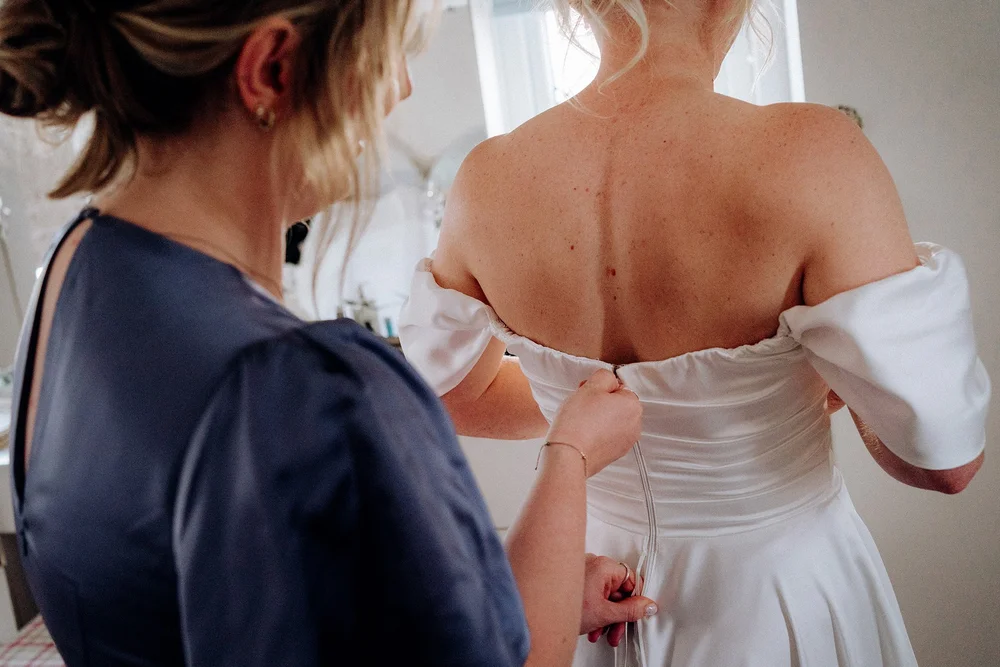 helping the bride into her dress