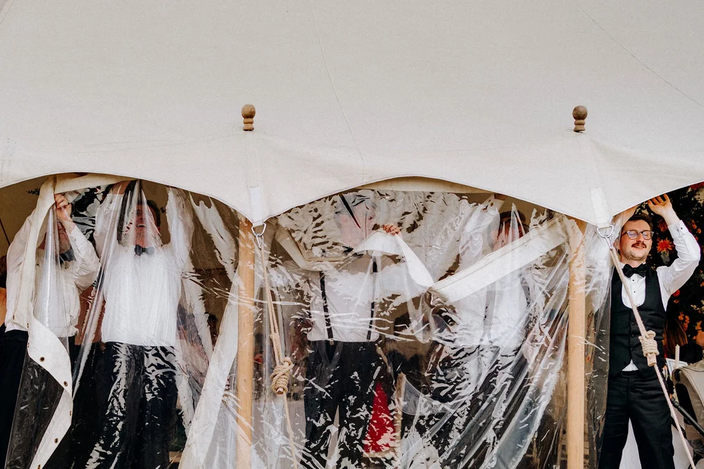 groom and groomsmen removing side from marquee