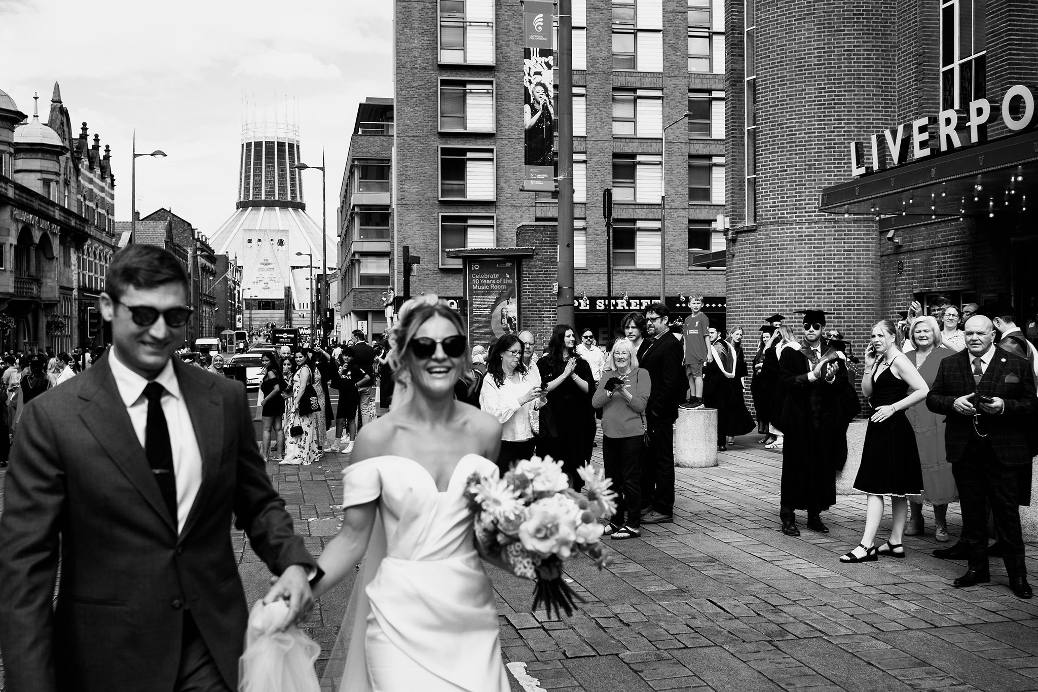 bride and groom take a walk on hope street as graduates look on
