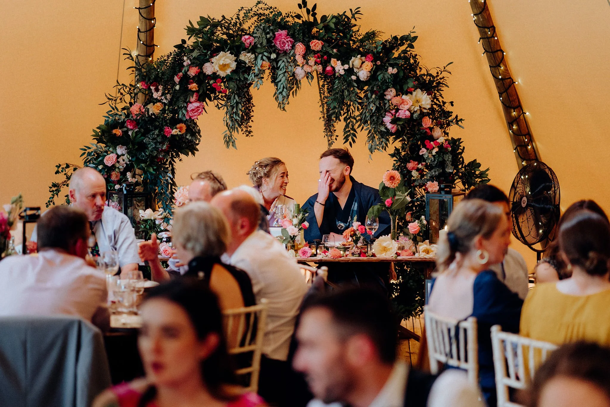 bride and groom laughing at the top table, tipis at riley green