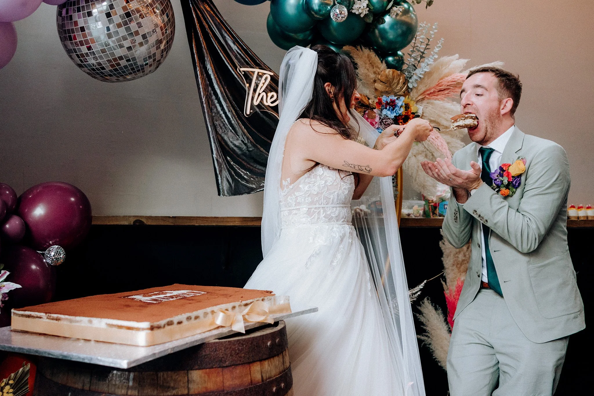 bride feeding her husband a huge slice of tiramisu 