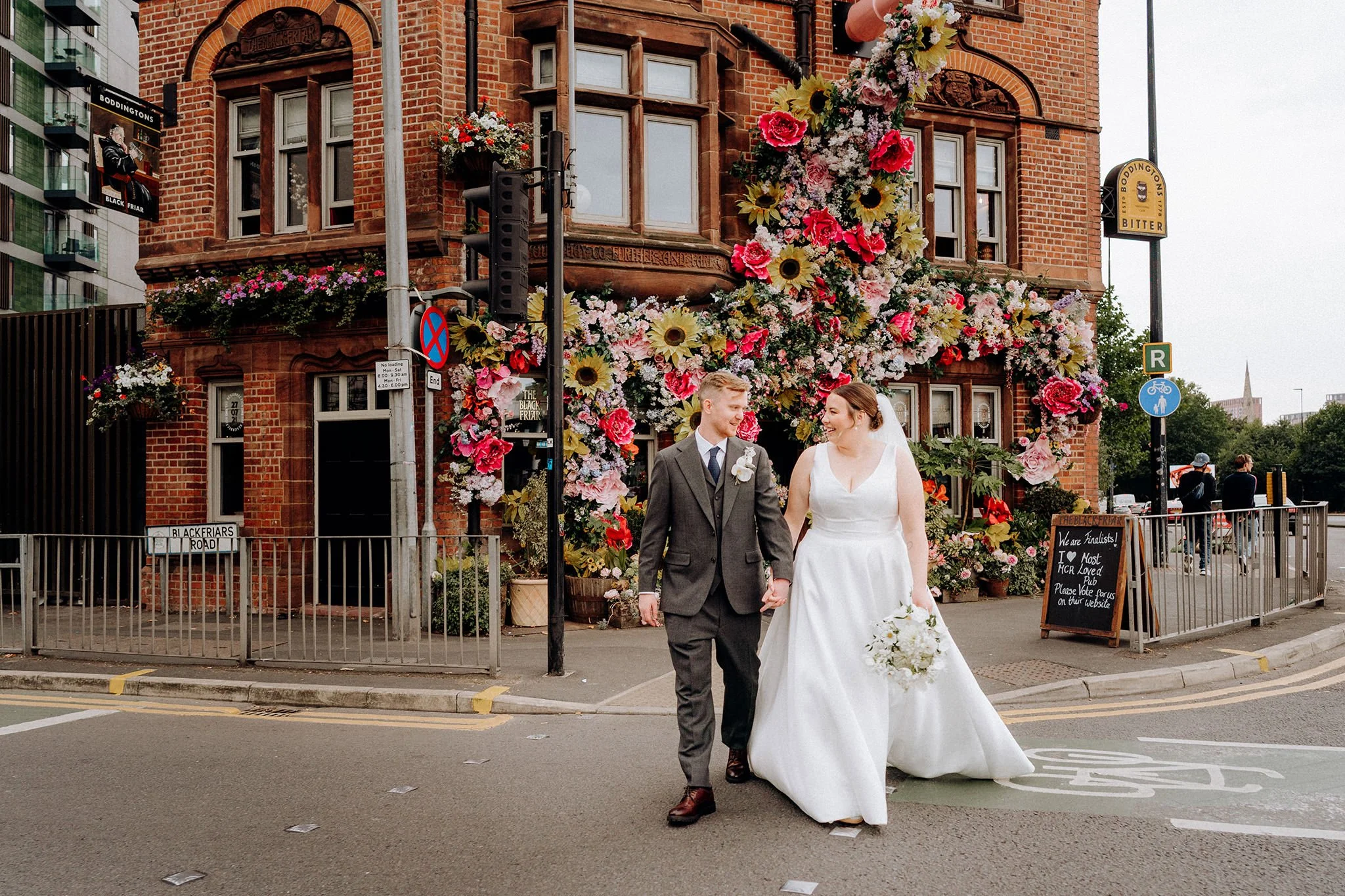 bride and groom cross road outside the black friar, salford