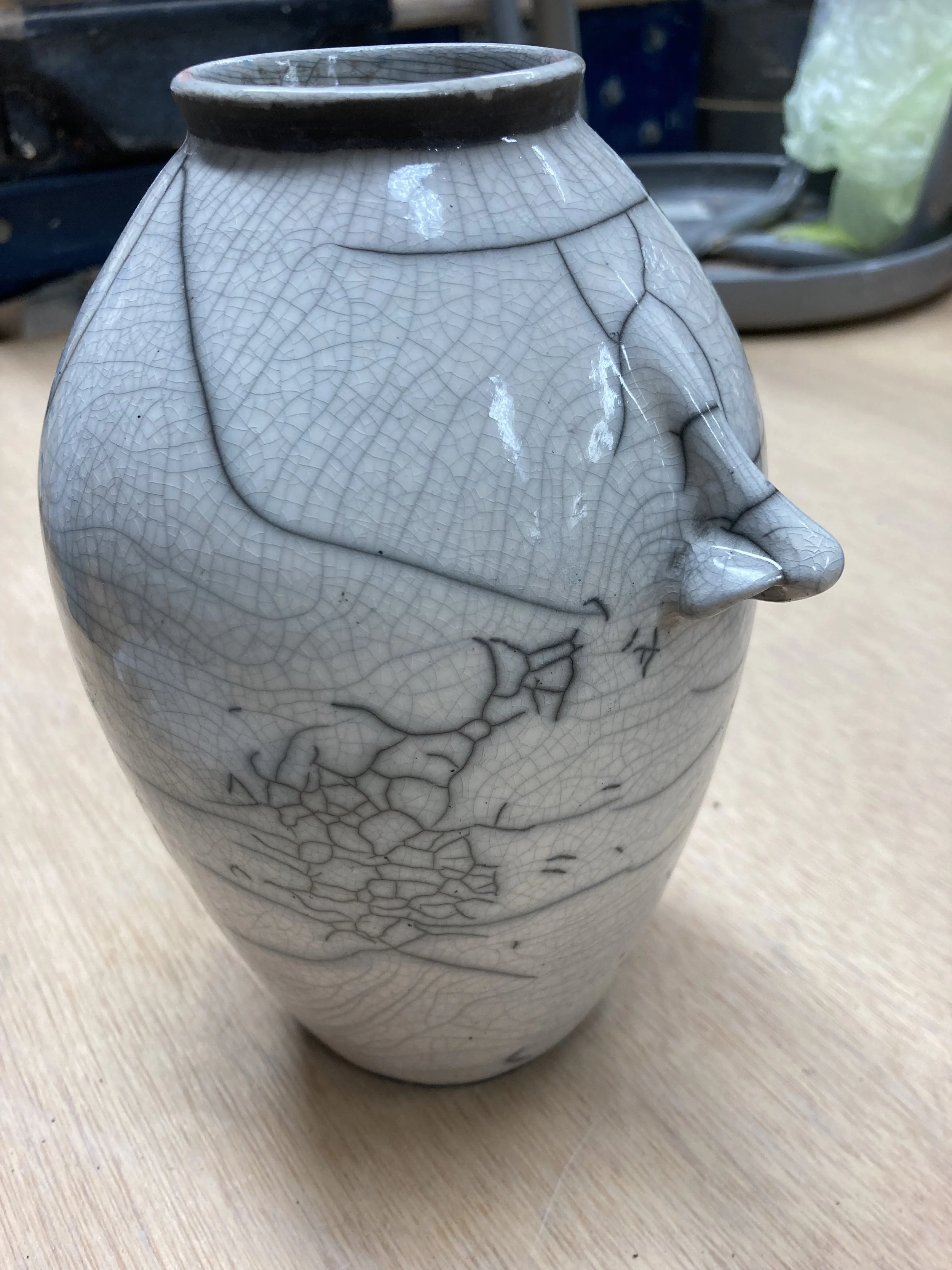 A ceramic vase with a crackle glaze finish and abstract black line design.