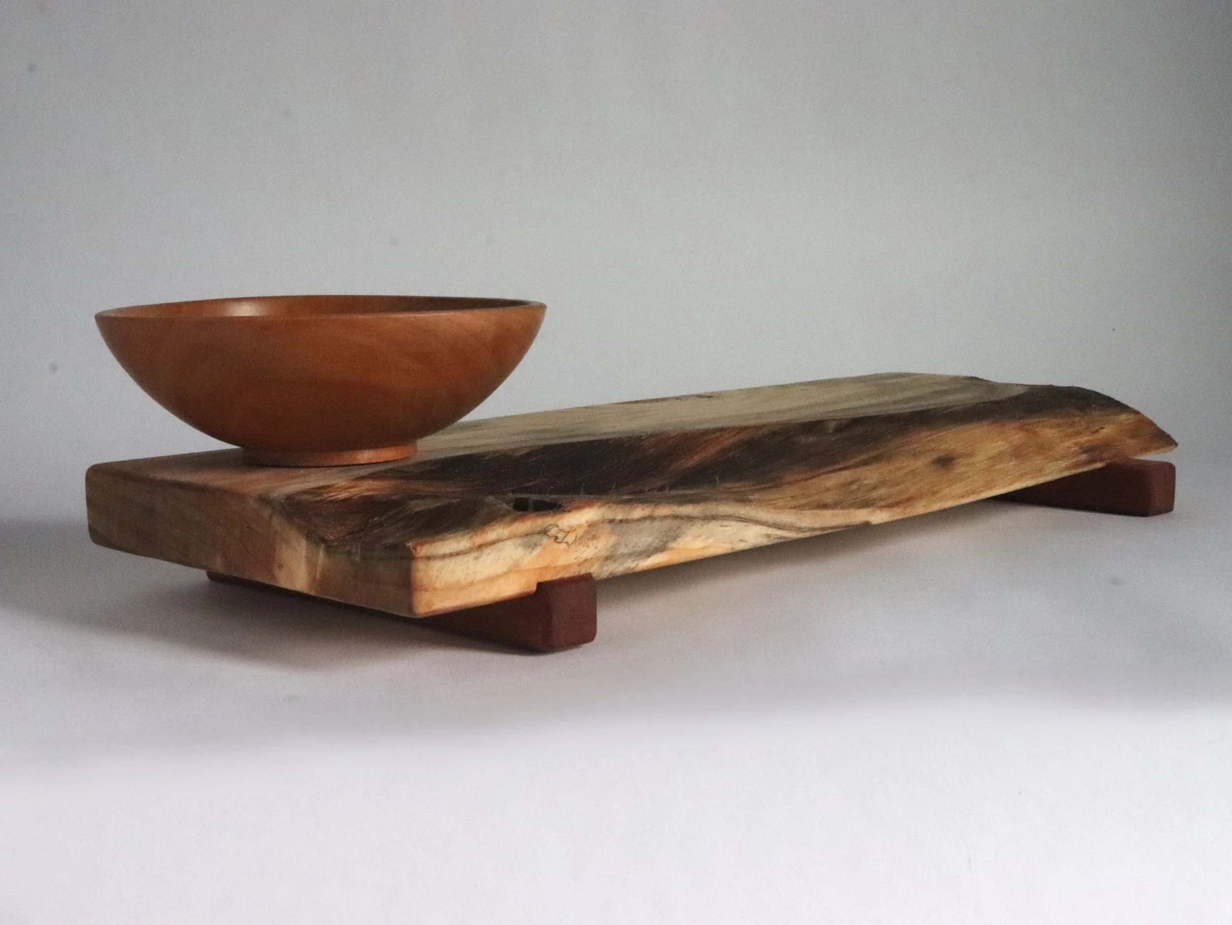 Low angle view of serving tray short end showcasing natural live edge depth, spalted spruce gradation, and pear bowl positioning
