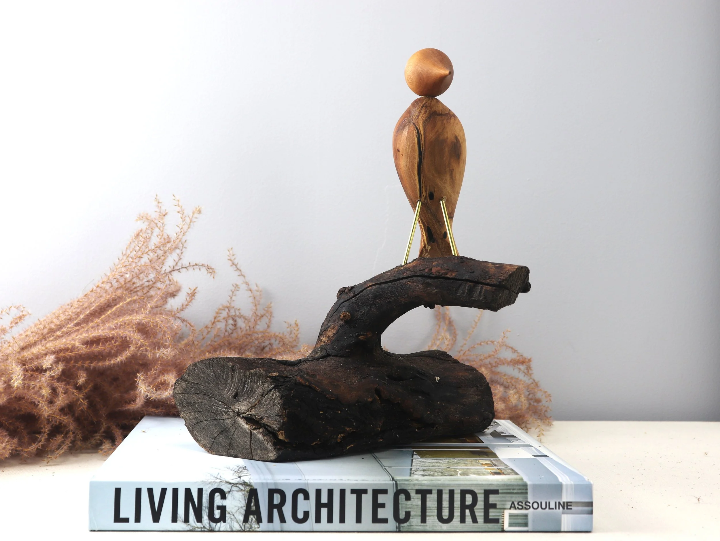 Contemplative Bird sculpture left side angle showing hand-carved bird tail and contrasting wood tones