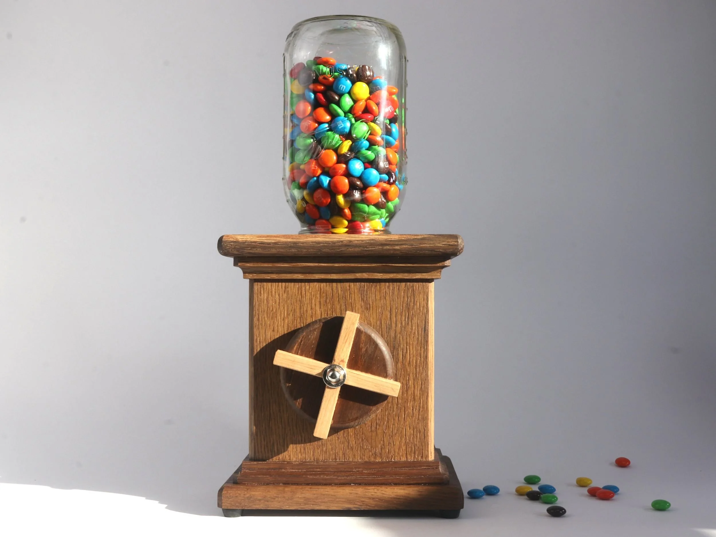 Handmade fumed white oak candy dispenser with maple X detail crank filled with colorful candy