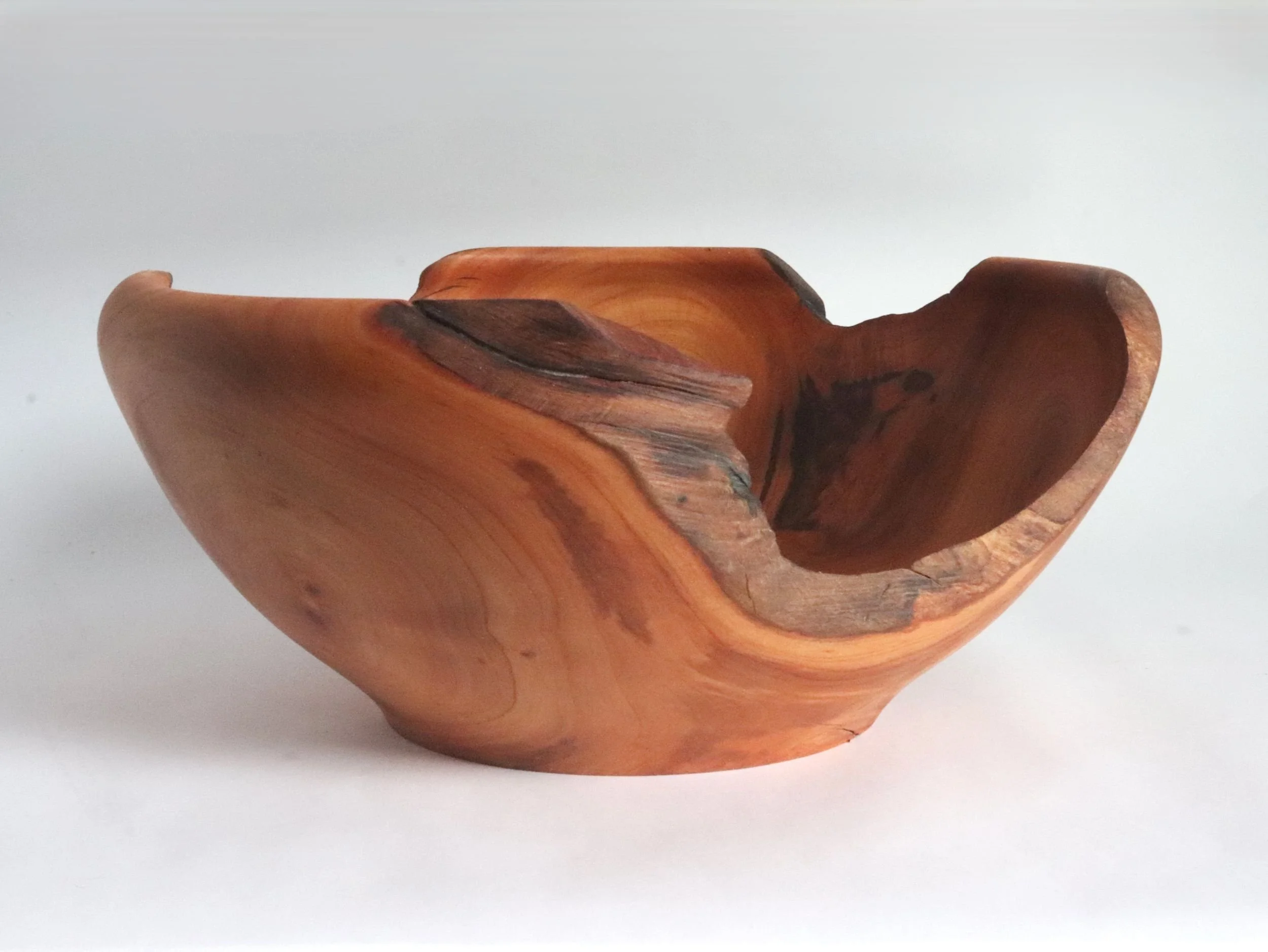 Handcrafted reclaimed cherry wood bowl showing natural live edge cutouts alternating with turned rim, displaying rich patinated cherry grain patterns