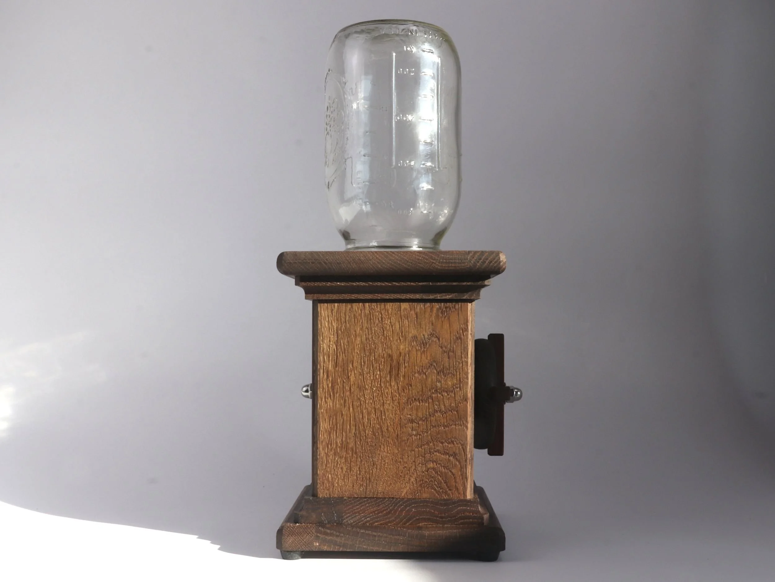 Side profile of handmade wooden candy dispenser showing chocolate brown fumed oak base and glass jar