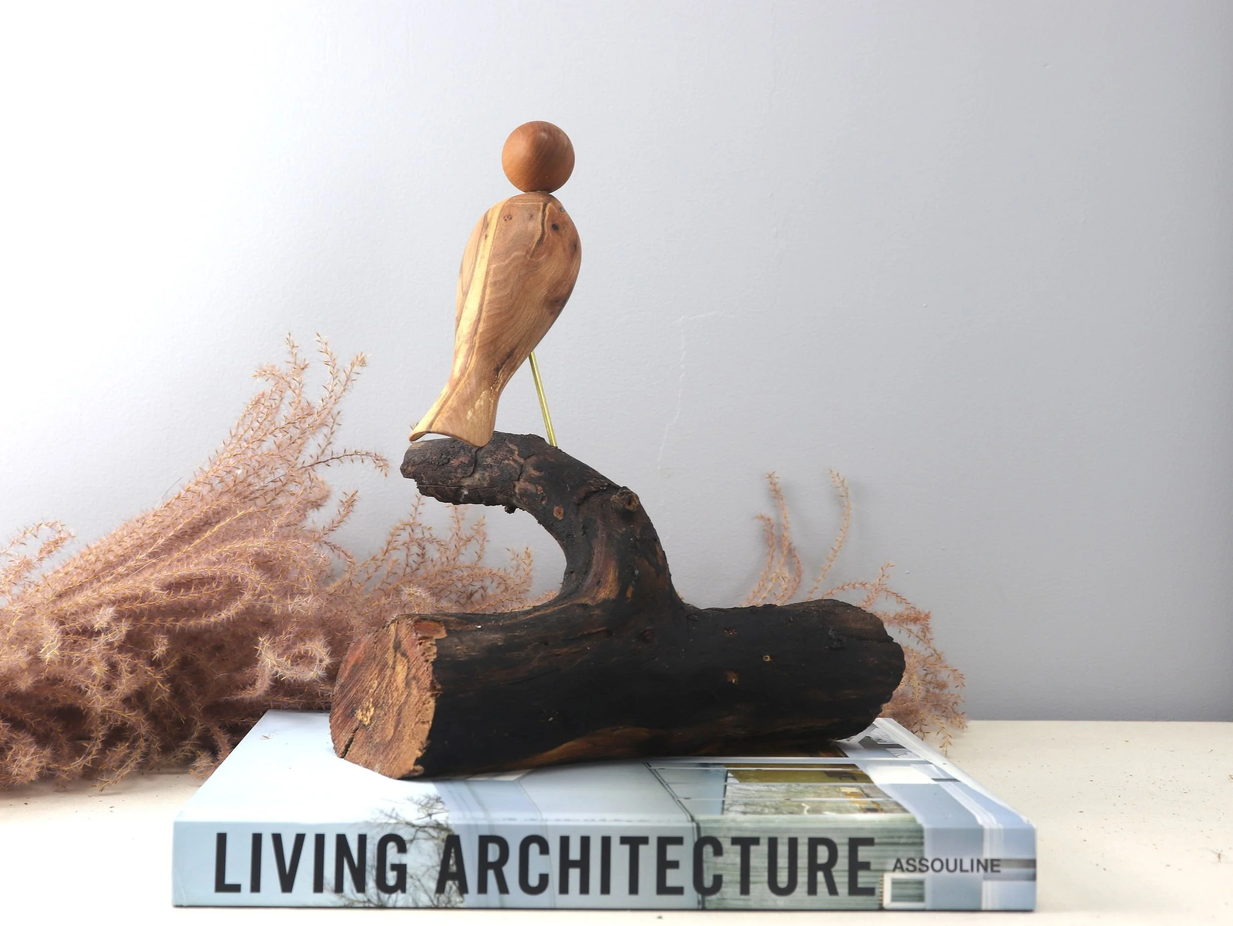 Wooden bird sculpture showing side profile of dogwood carved bird with mahogany head on natural horizontal log