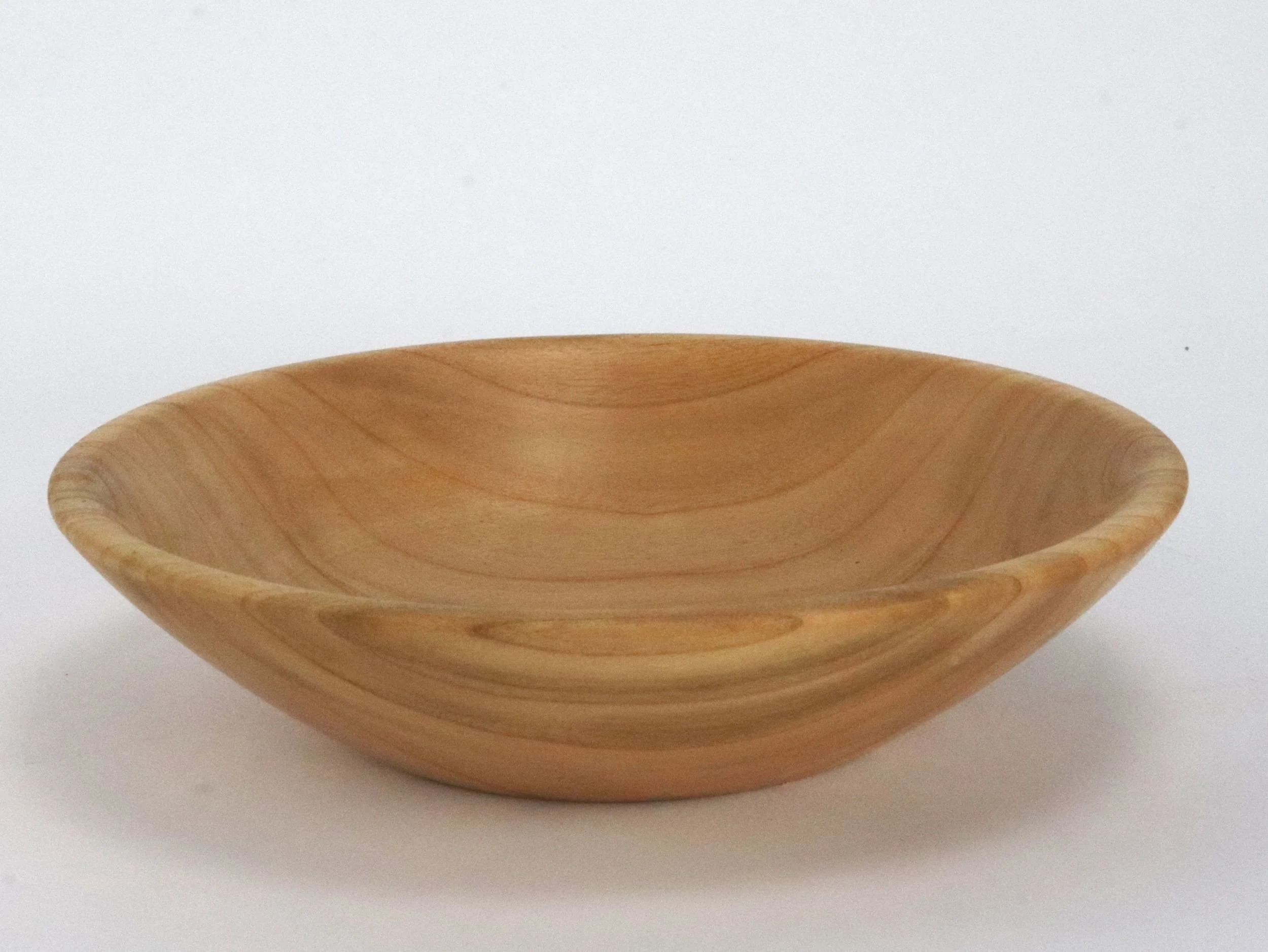 Close up of handmade maple bowl showing natural light wood grain patterns and smooth finish