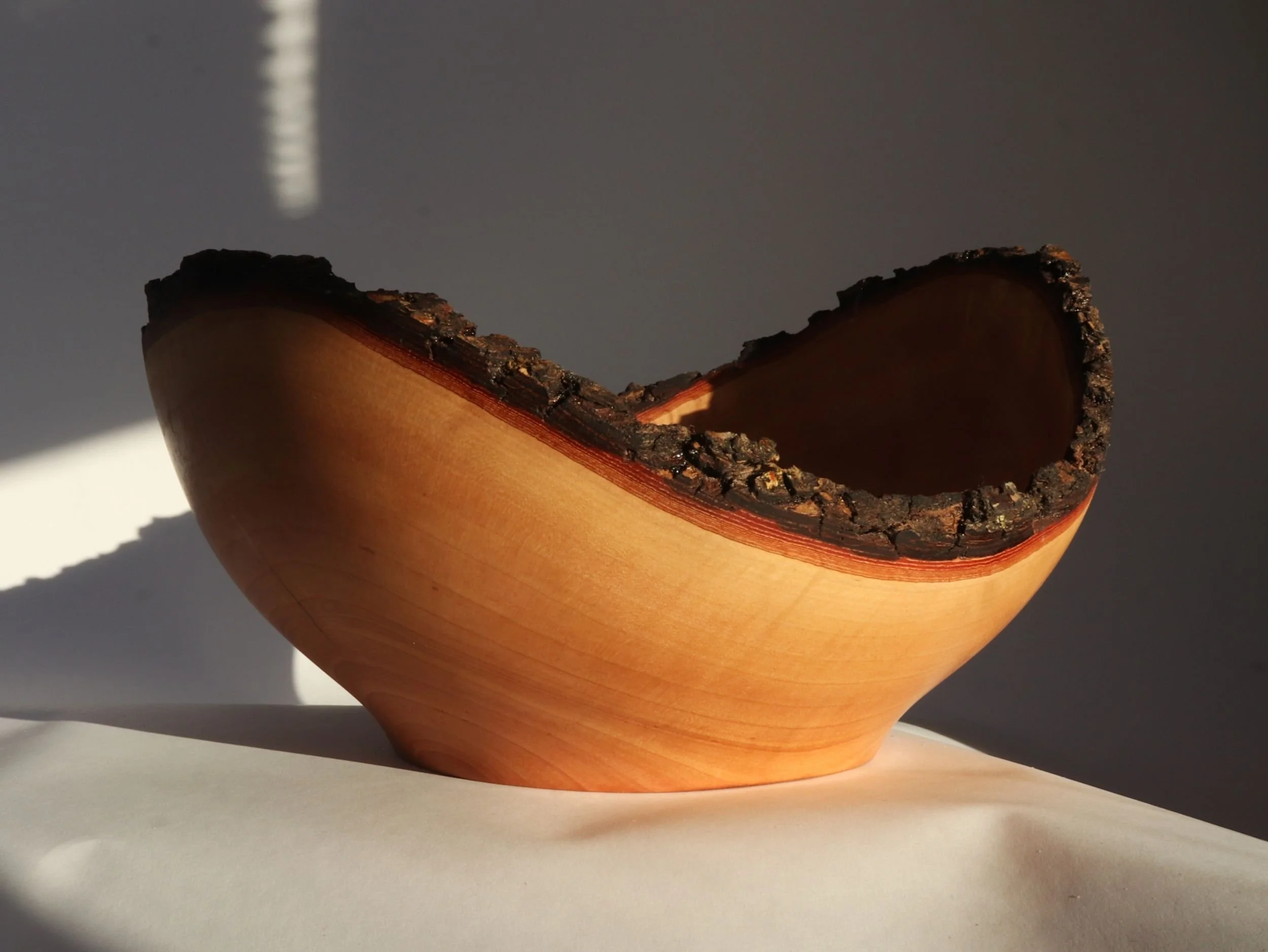 Handmade cherry bowl lowest side showing natural live edge bark contrast with smooth wood finish
