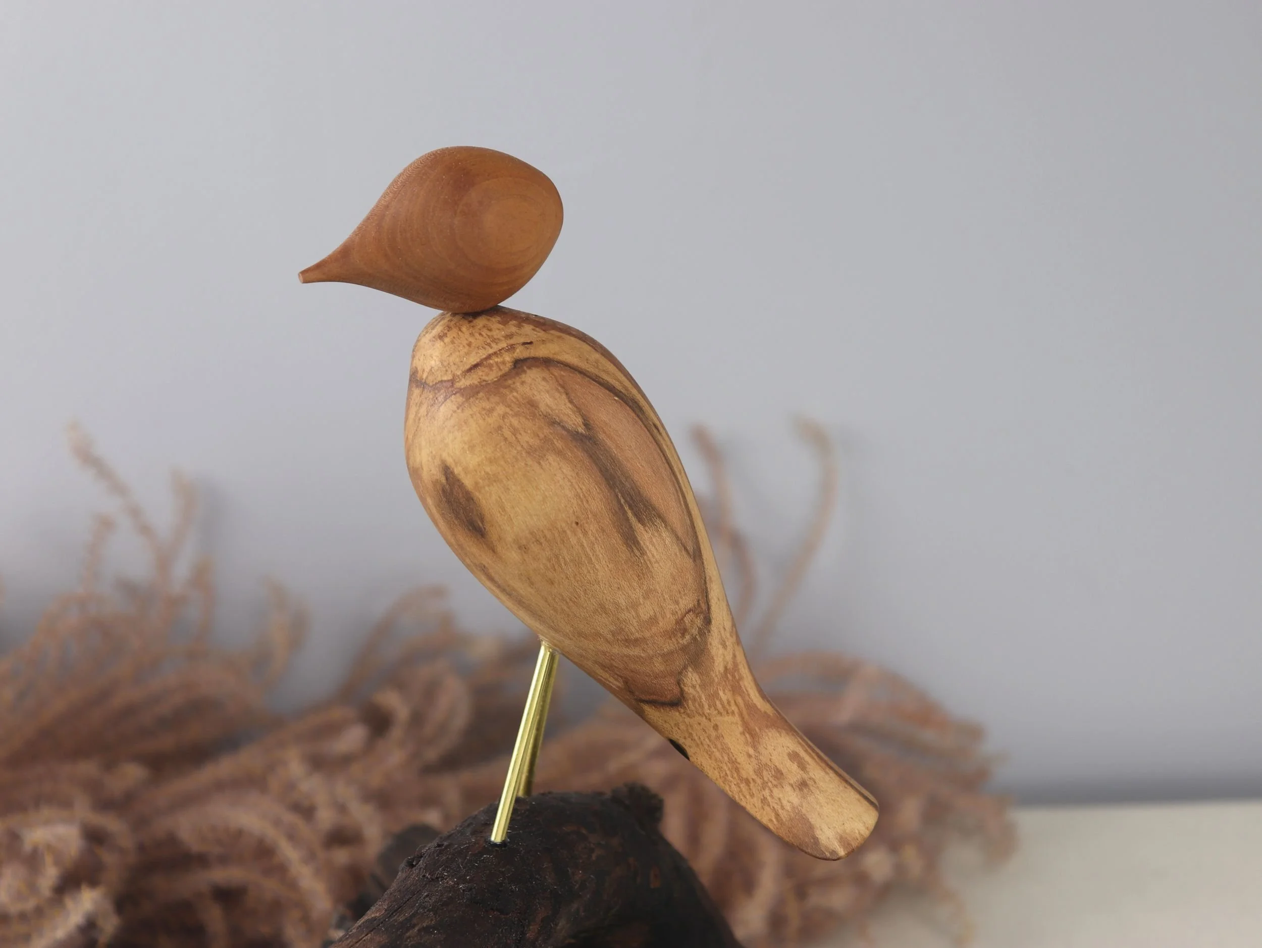Intimate view of contemplative bird sculpture highlighting mahogany head contrast and artistic wood details