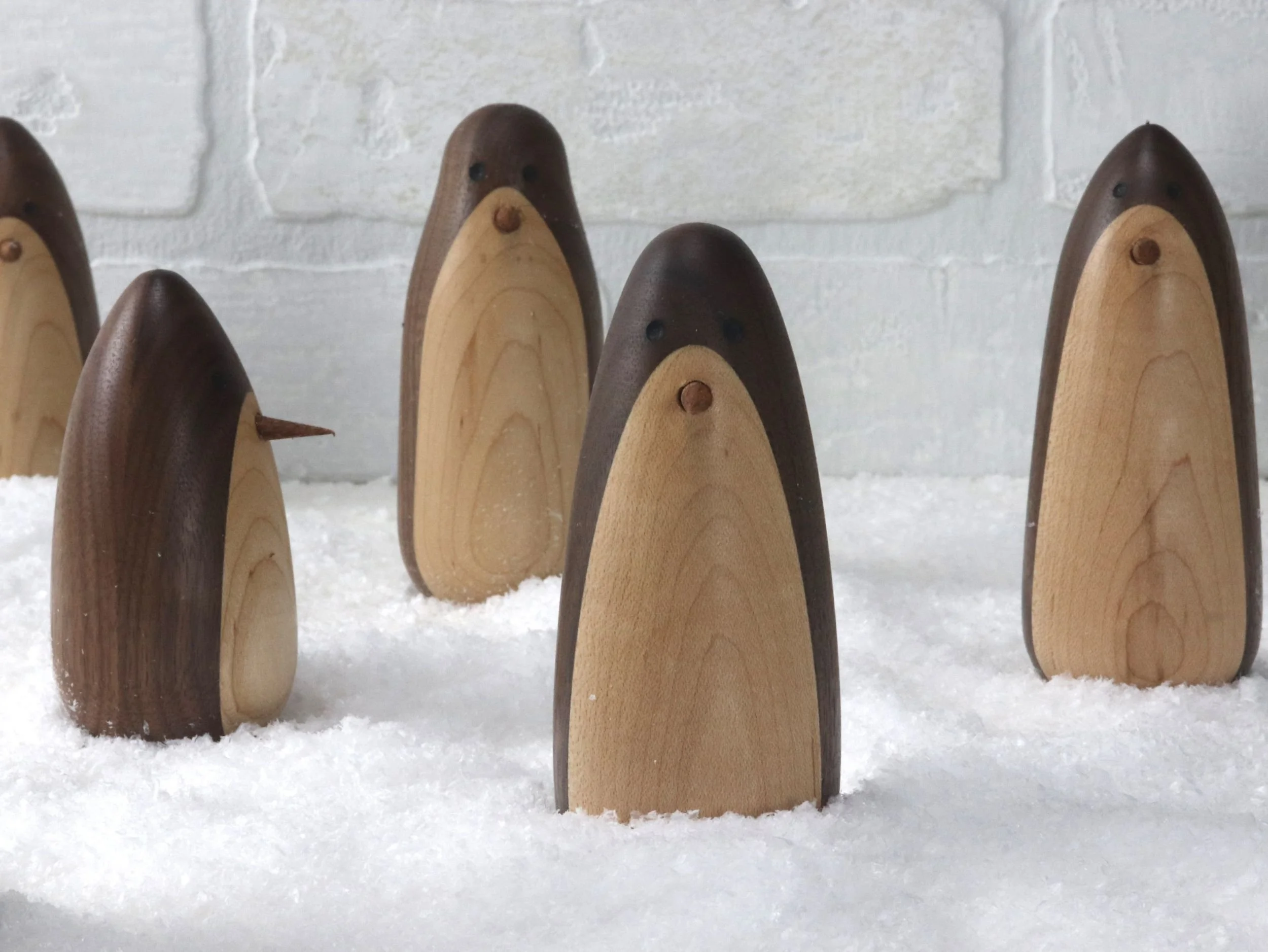 Group of handcrafted walnut and maple penguins displaying different profiles and unique personalities