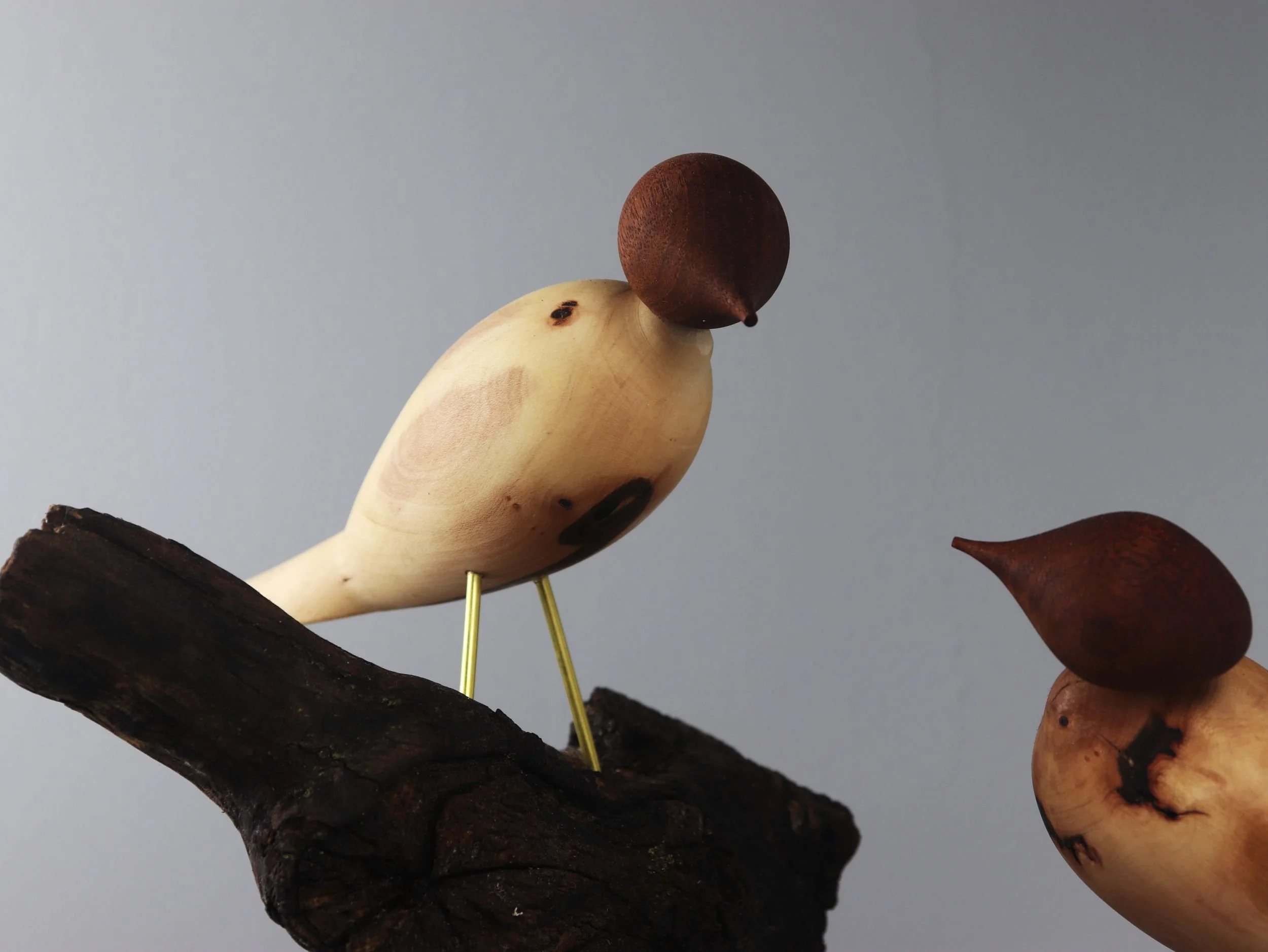Close up of carved wooden bird showing brass legs and hand-turned dogwood body with darker grain markings