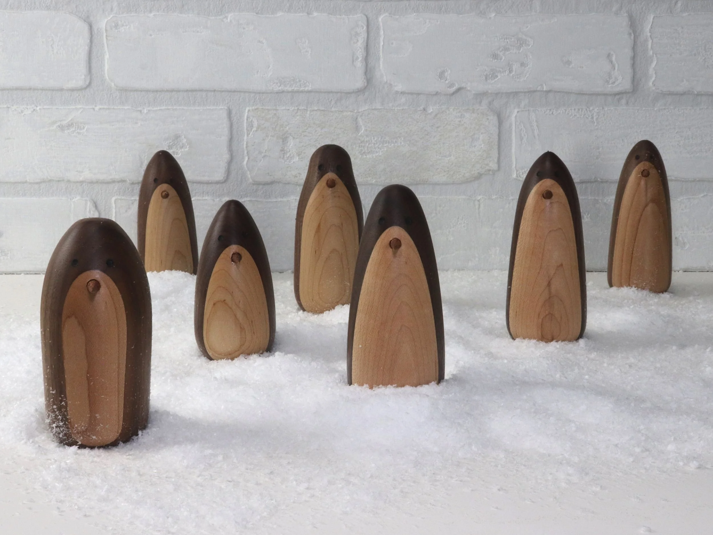Handmade wooden penguin figurines in walnut and maple showing size variations from 3.5 to 4.25 inches tall