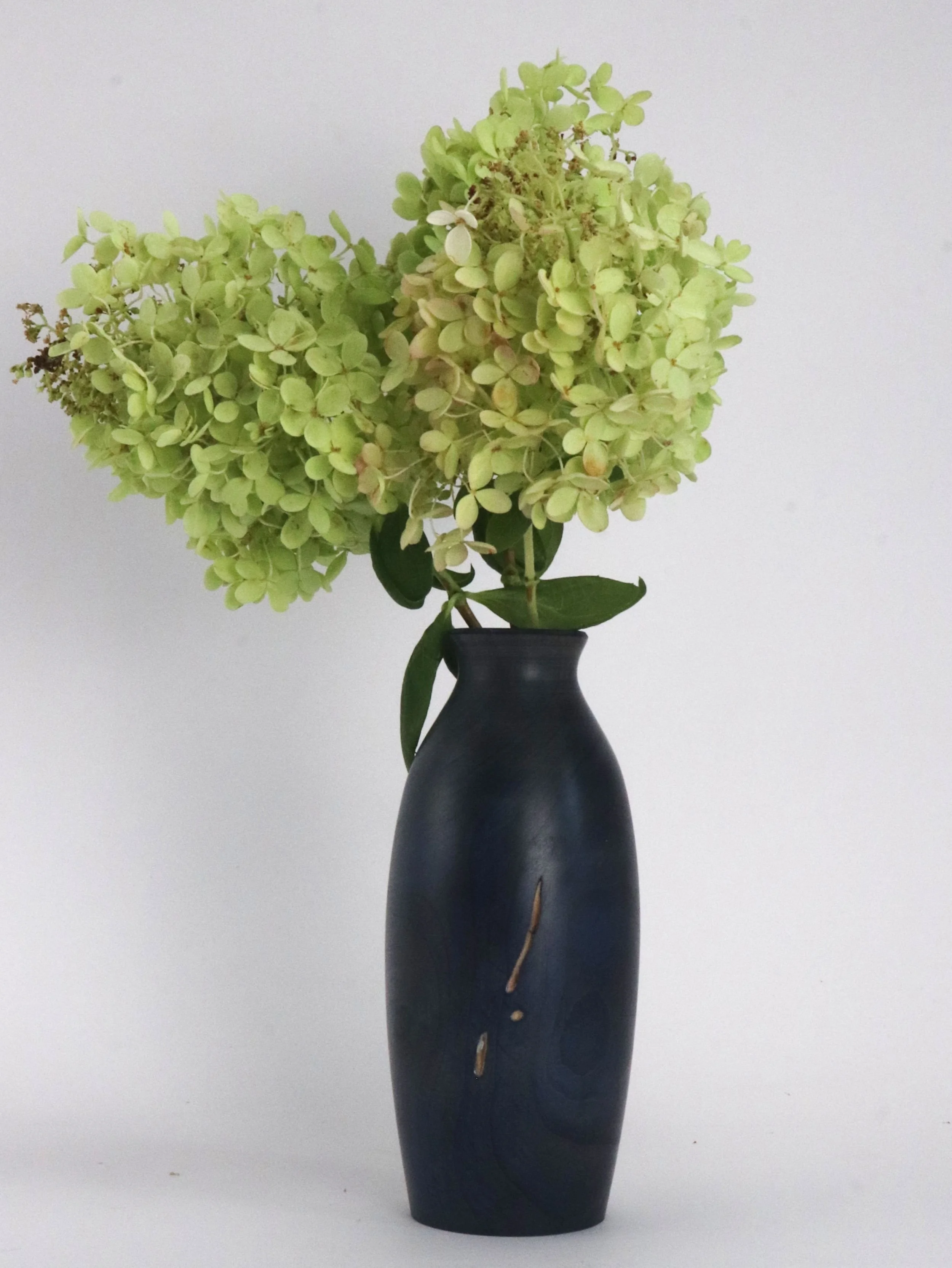 Unique navy blue maple vase with flowers displayed in modern home interior decor setting