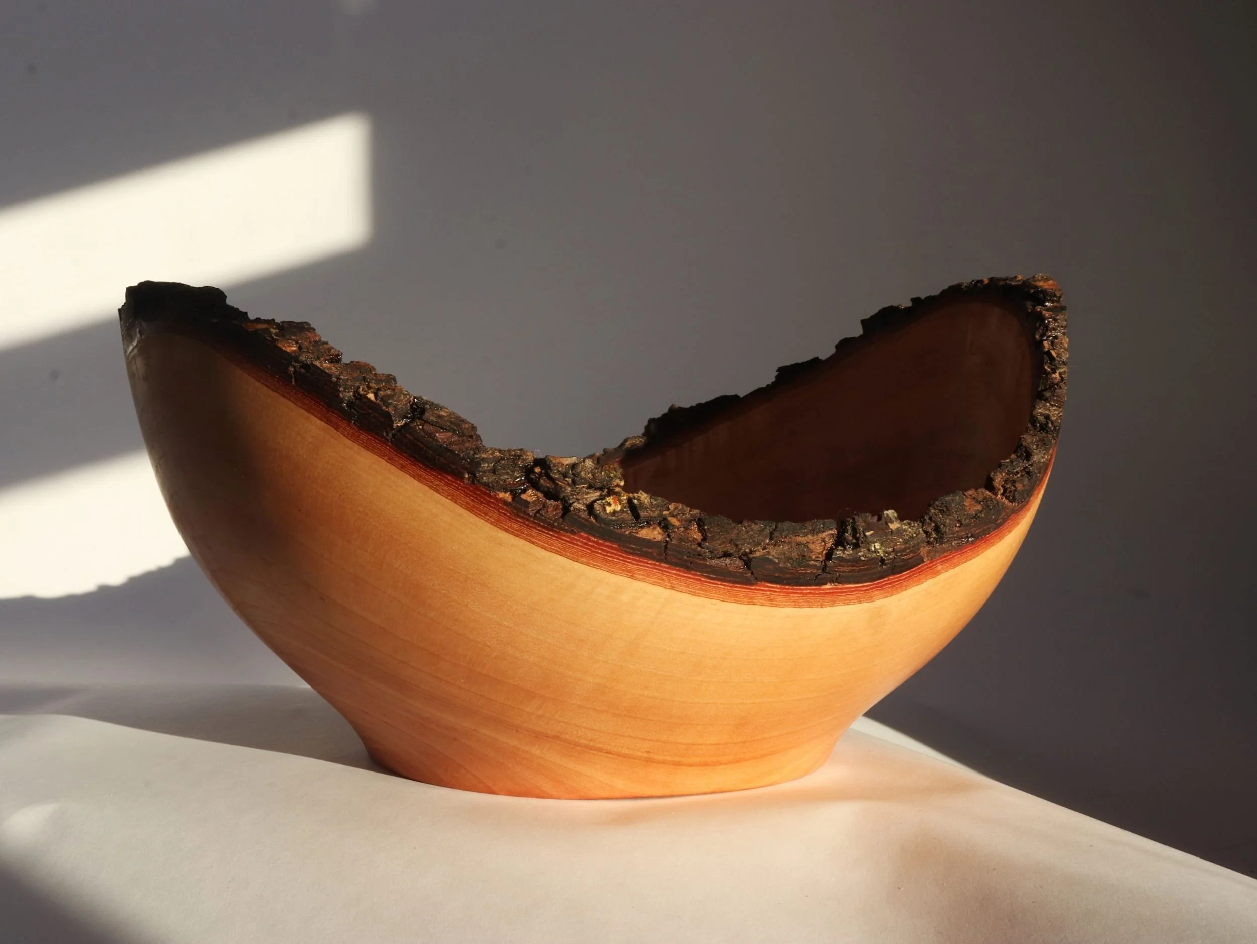 One of a kind cherry serving bowl short side view showing dramatic height variation and live edge detail