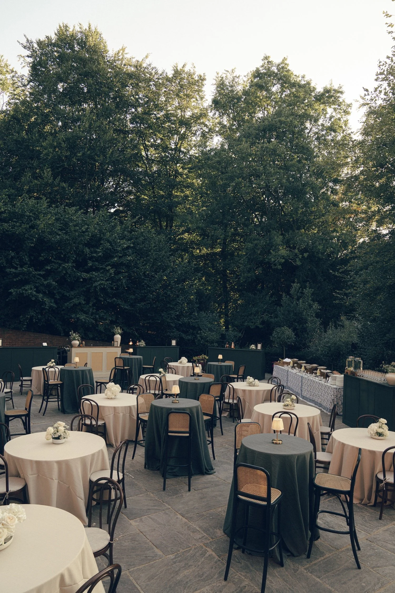 Outdoor wedding reception at Four Seasons Hampshire with dark wood bentwood and chateau bar stools and forest green Stow bar, and white floral arrangements