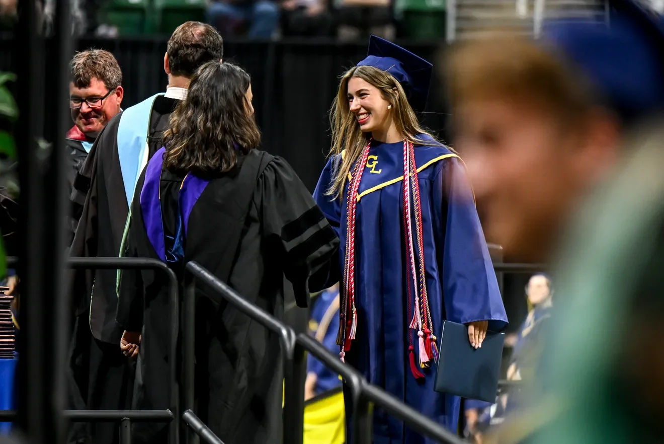 Nicole shaking hands with a GLHS graduate. Photo credit Lansing State Journal.