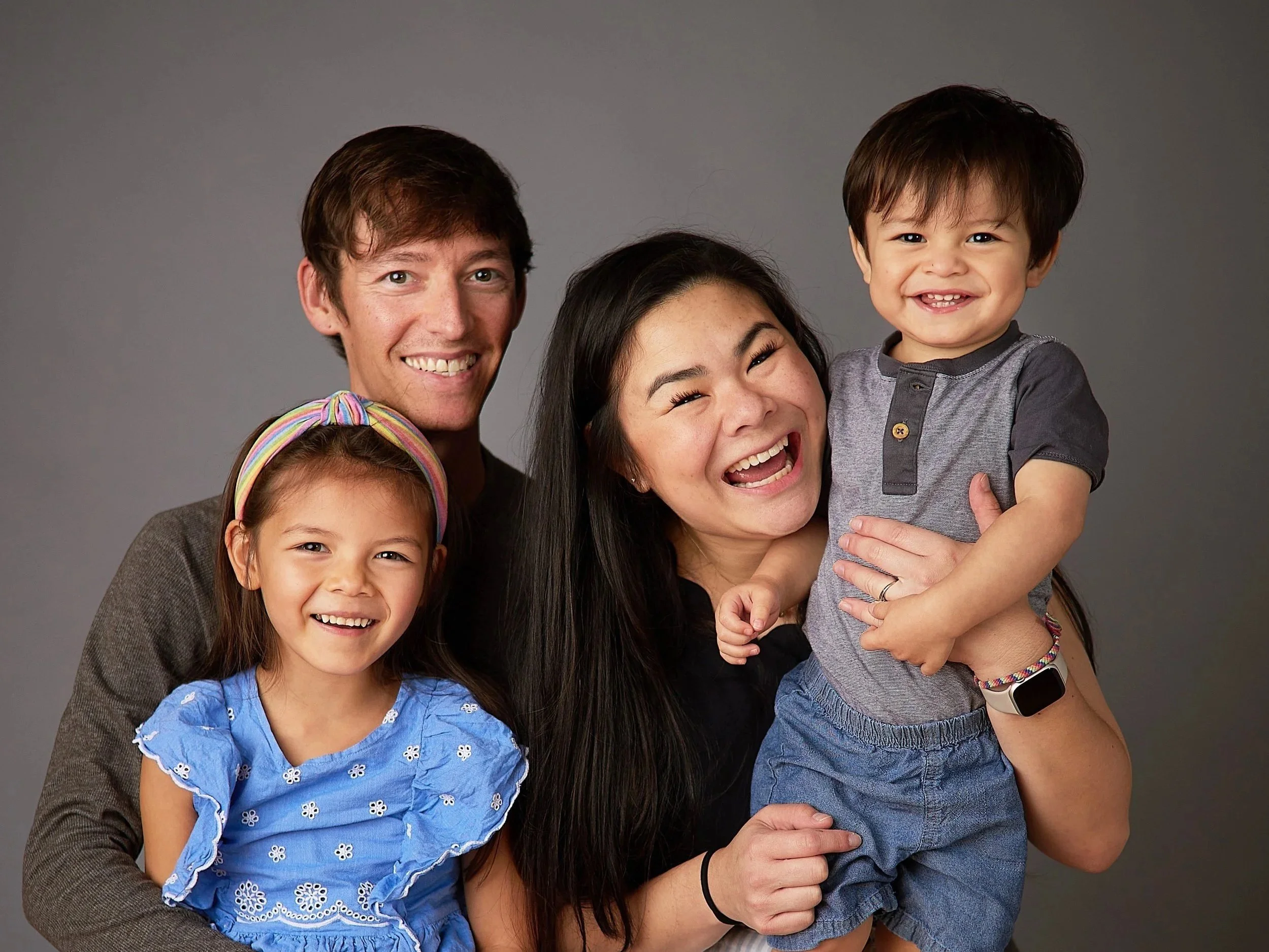 family with two young children laughing in a photo studio having fun