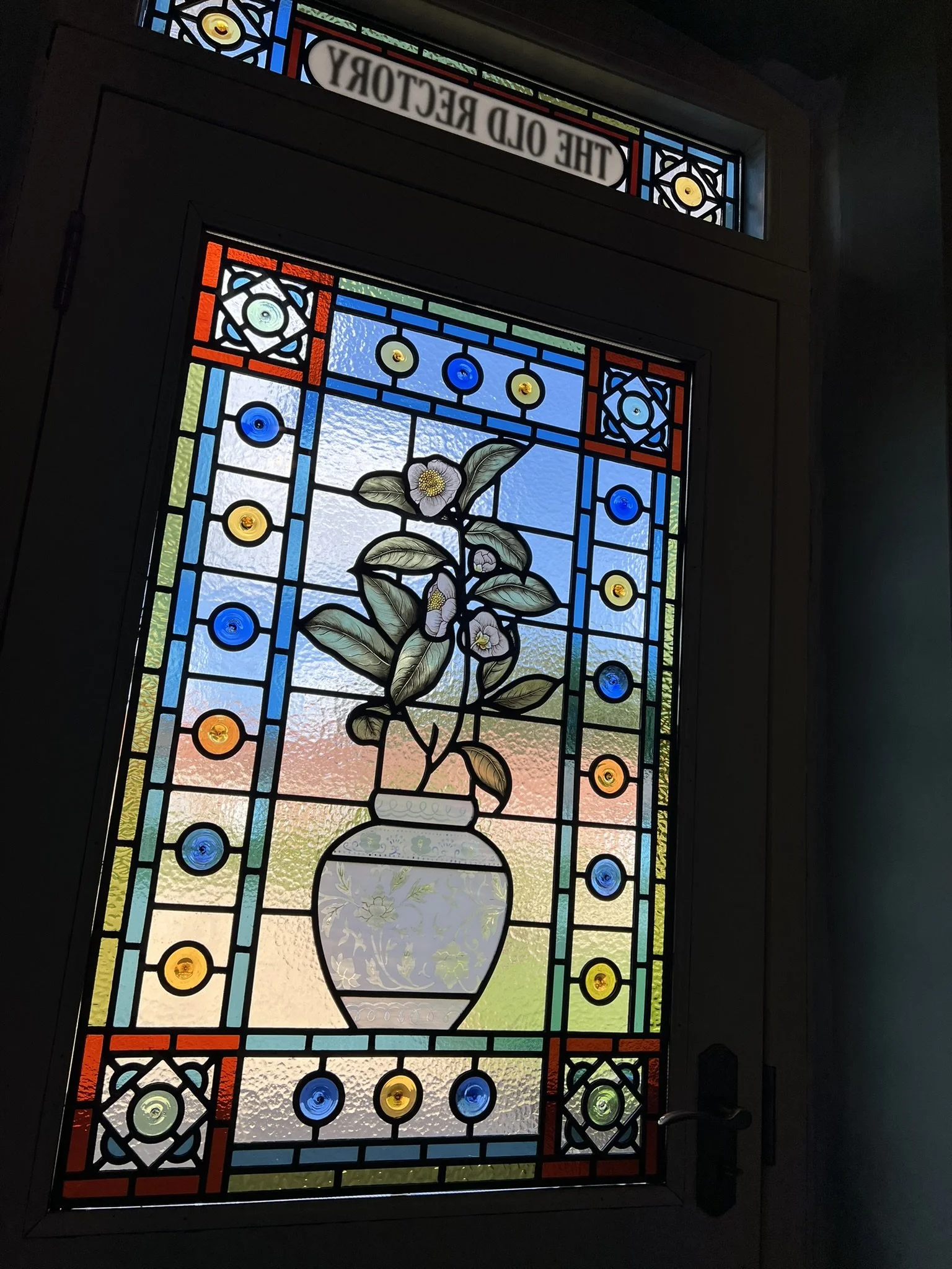 stained glass window in Victorian style, featuring an intricate vase design with flowers, leaves and mouth-blown roundels and hand painted, kiln fired house name