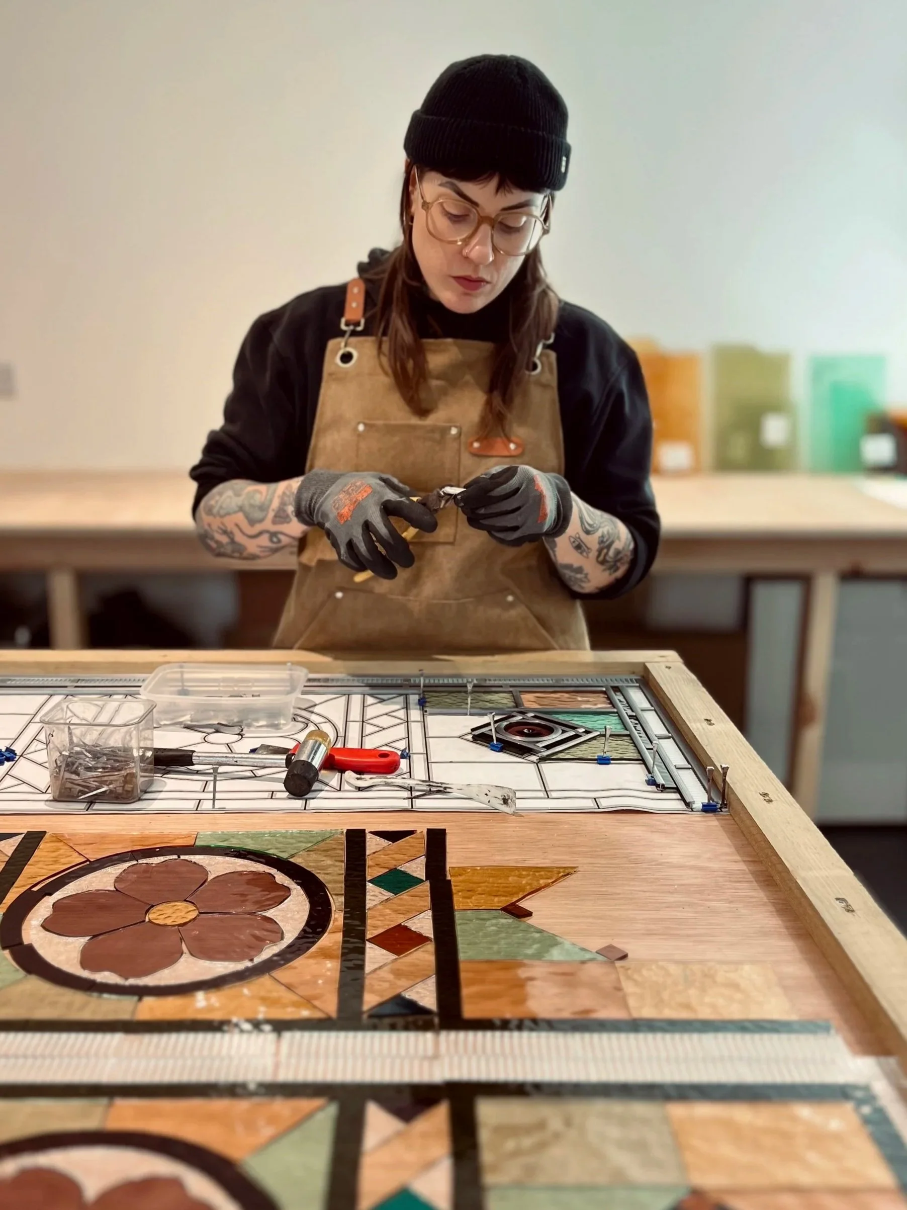 Danielle Croft, owner of Luna Glassworks Stained Glass Studio. Image shows Danielle building a stained glass window in her workshop.